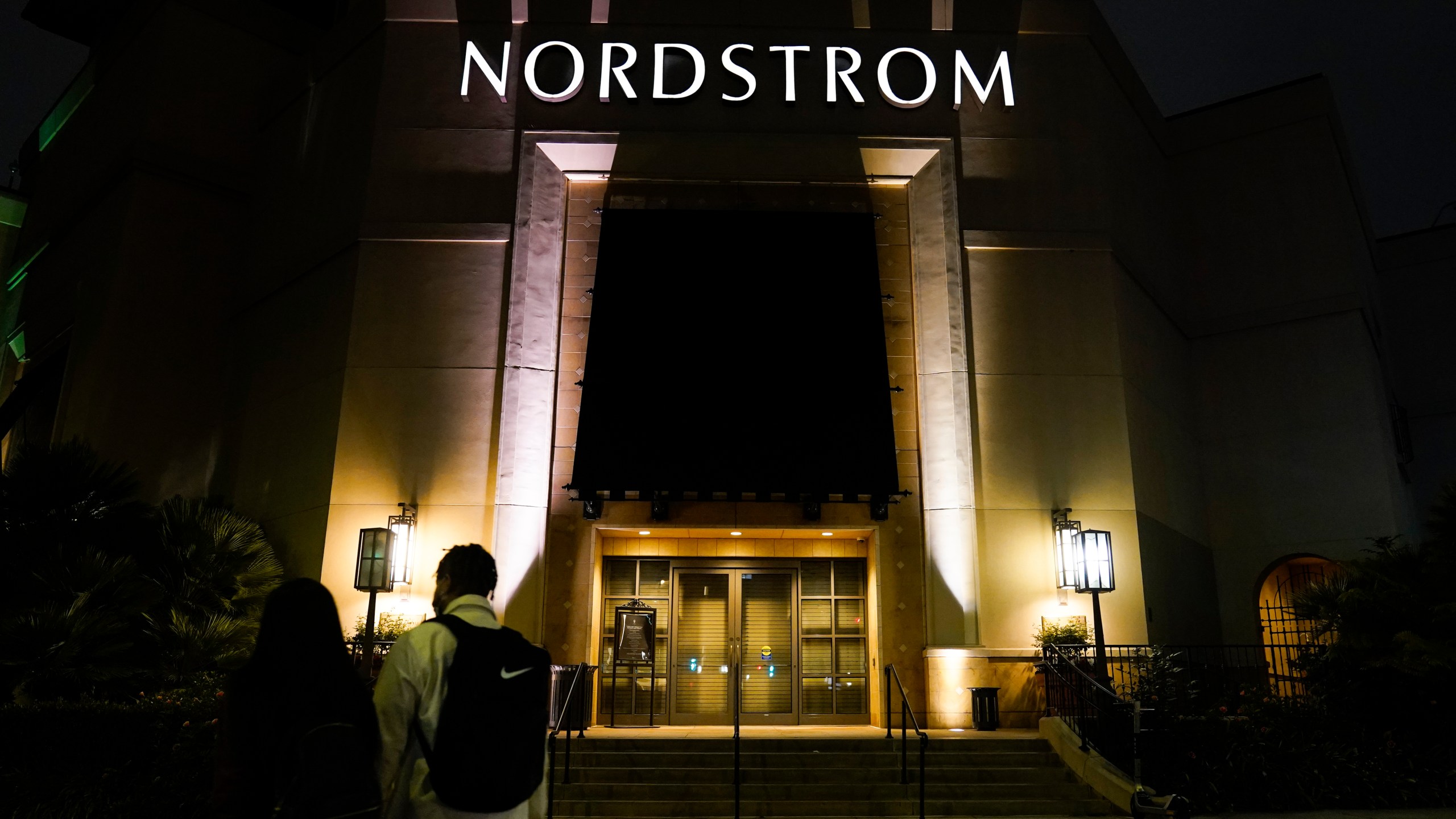 FILE - Two pedestrians walk near an entrance to a Nordstrom department store at the Grove mall in Los Angeles, Dec. 2, 2021. Bruce Nordstrom, a retail executive who helped expand his family’s Pacific Northwest department store chain into an upscale national brand, has died. Seattle-based Nordstrom Inc. said its former chairman died at his home, Saturday, May 18, 2024. He was 90. (AP Photo/Jae C. Hong, File)