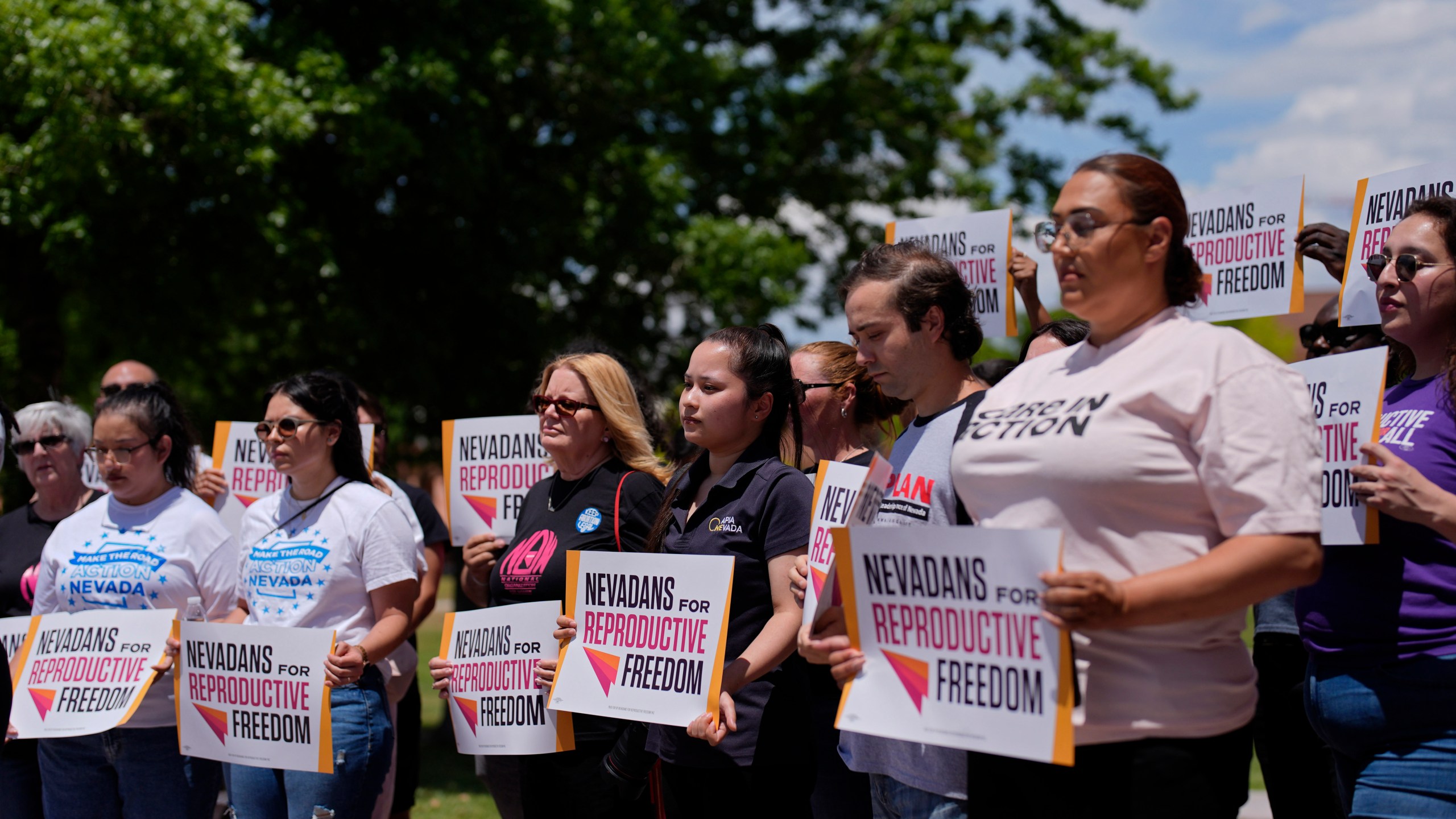 People hold signs during a news conference by Nevadans for Reproductive Freedom, Monday, May 20, 2024, in Las Vegas. Abortion access advocates in Nevada said Monday they've submitted twice the number of petition signatures needed to qualify for a ballot measure aimed at enshrining what they term reproductive rights in the state constitution. (AP Photo/John Locher)