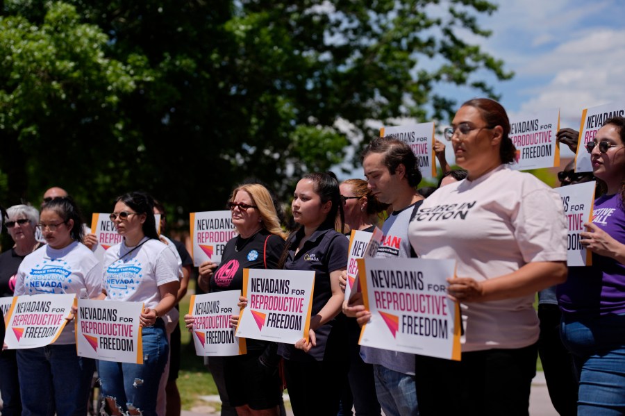 People hold signs during a news conference by Nevadans for Reproductive Freedom, Monday, May 20, 2024, in Las Vegas. Abortion access advocates in Nevada said Monday they've submitted twice the number of petition signatures needed to qualify for a ballot measure aimed at enshrining what they term reproductive rights in the state constitution. (AP Photo/John Locher)