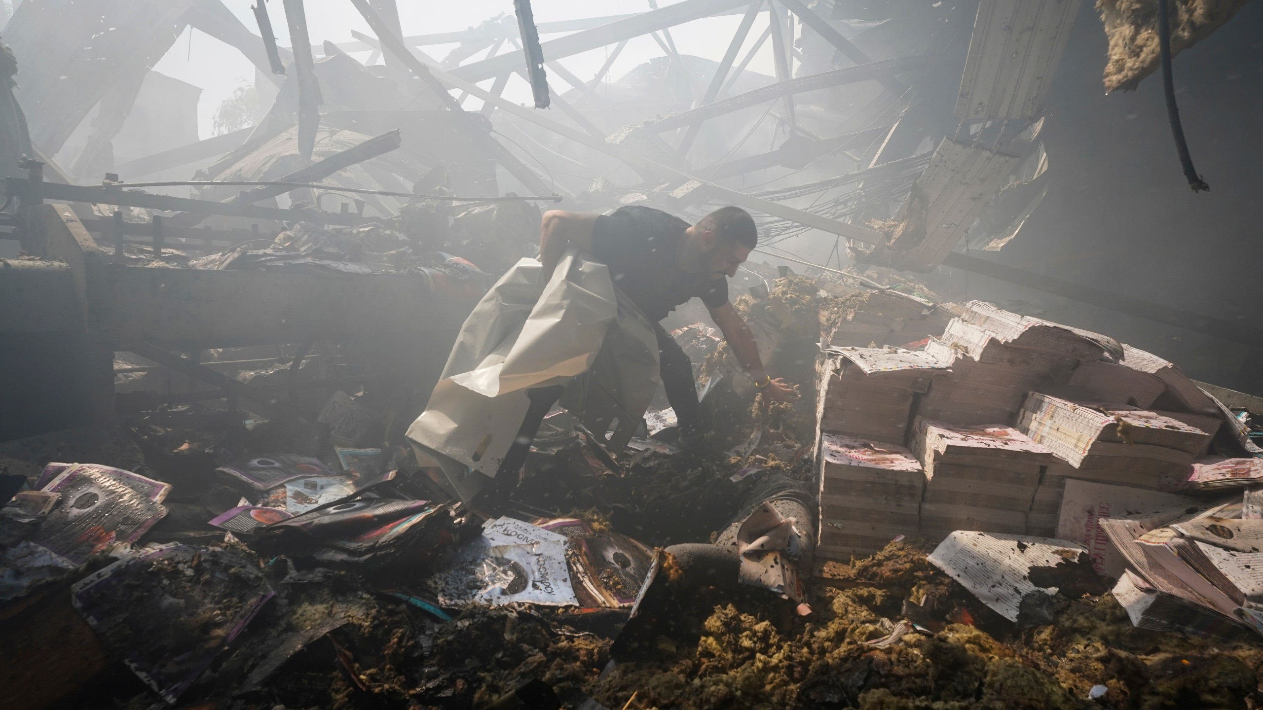 A rescuer recovers a lifeless body from under the rubble after a Russian missile hit a printing house in Kharkiv, Ukraine.