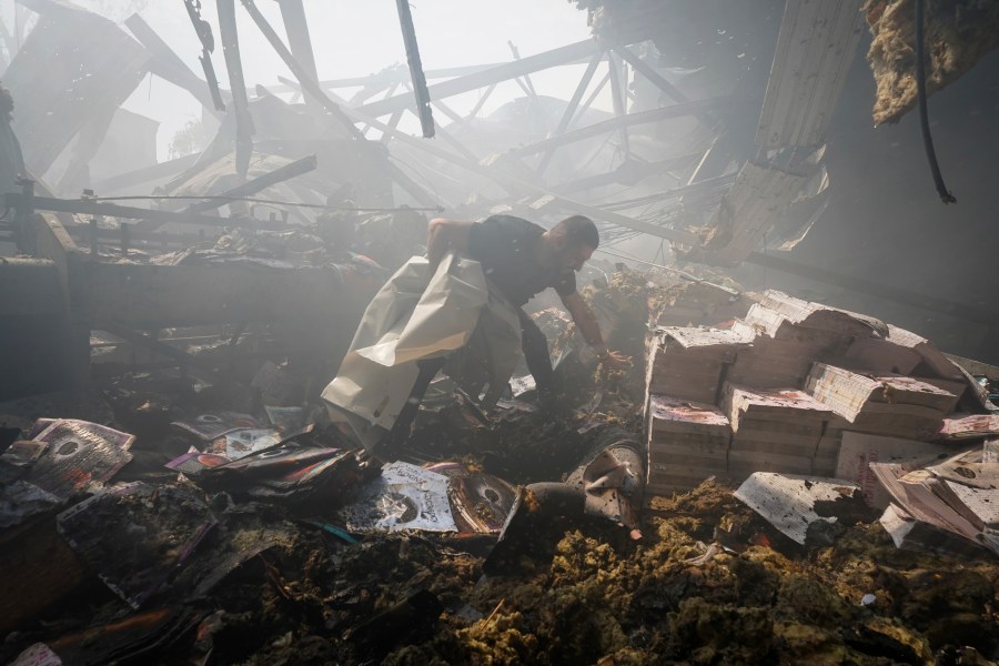 A rescuer recovers a lifeless body from under the rubble after a Russian missile hit a printing house in Kharkiv, Ukraine.