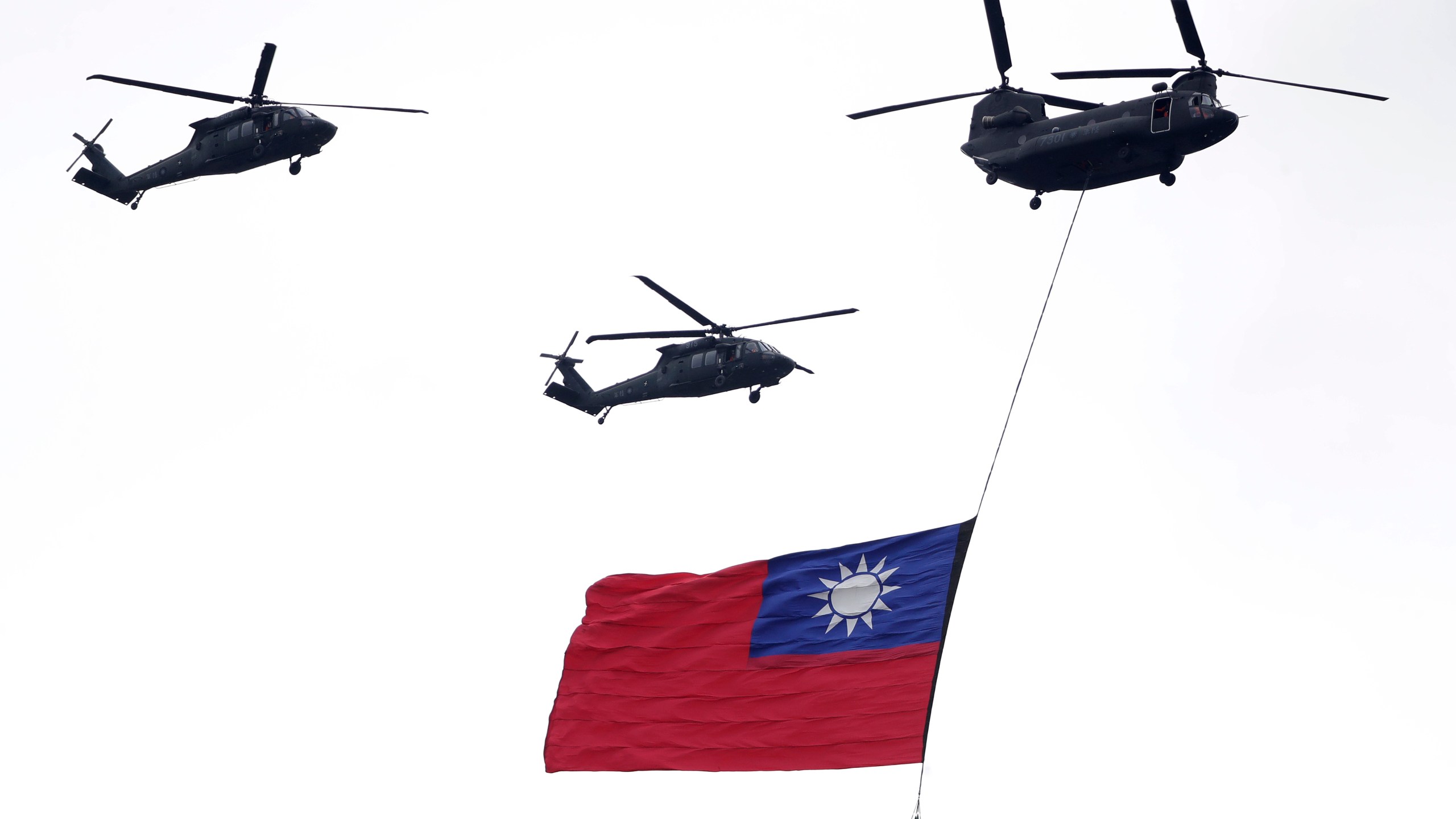 FILE - Helicopters fly over with Taiwan national flag during an inauguration celebration of Taiwan's President Lai Ching-te in Taipei, Taiwan, on May 20, 2024. China's military held exercises surrounding Taiwan on Thursday, May 23, 2024, in what it called punishment for separatist forces seeking independence on the self-governed island where a new president took office this week. (AP Photo/Chiang Ying-ying, File)