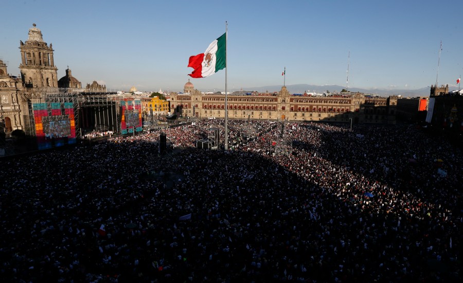 FILE - People gather in the Zocalo to celebrate Mexico's newly sworn-in president, Andres Manuel Lopez Obrador, in Mexico City, Dec. 1, 2018. Lopez Obrador swept into office with the motto laying out his administration’s priorities: “For the good of all, first the poor.” (AP Photo/Marco Ugarte, File)