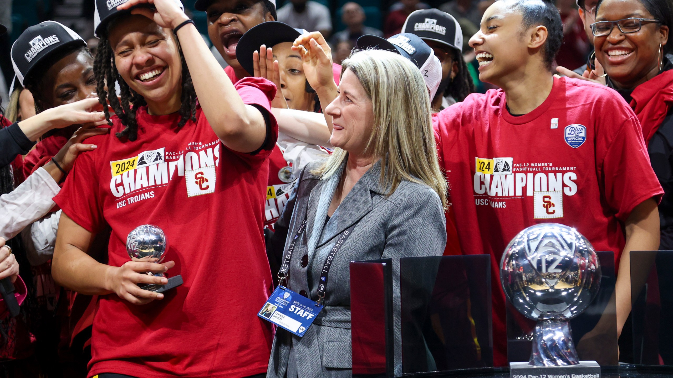 FILE - Southern California's McKenzie Forbes reacts after being presented the Pac-12 tournament Most Valuable Player trophy by Pac-12 Commissioner Teresa Gould after USC defeated Stanford in an NCAA college basketball game for the championship of the Pac-12 tournament March 10, 2024, in Las Vegas. The NCAA and the nation's five biggest conferences have agreed to pay nearly $2.8 billion to settle a host of antitrust claims,a monumental decision that sets the stage for a groundbreaking revenue-sharing model that could start directing millions of dollars directly to athletes as soon as the 2025 fall semester. (AP Photo/Ian Maule, File)