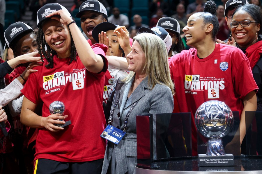 FILE - Southern California's McKenzie Forbes reacts after being presented the Pac-12 tournament Most Valuable Player trophy by Pac-12 Commissioner Teresa Gould after USC defeated Stanford in an NCAA college basketball game for the championship of the Pac-12 tournament March 10, 2024, in Las Vegas. The NCAA and the nation's five biggest conferences have agreed to pay nearly $2.8 billion to settle a host of antitrust claims,a monumental decision that sets the stage for a groundbreaking revenue-sharing model that could start directing millions of dollars directly to athletes as soon as the 2025 fall semester. (AP Photo/Ian Maule, File)