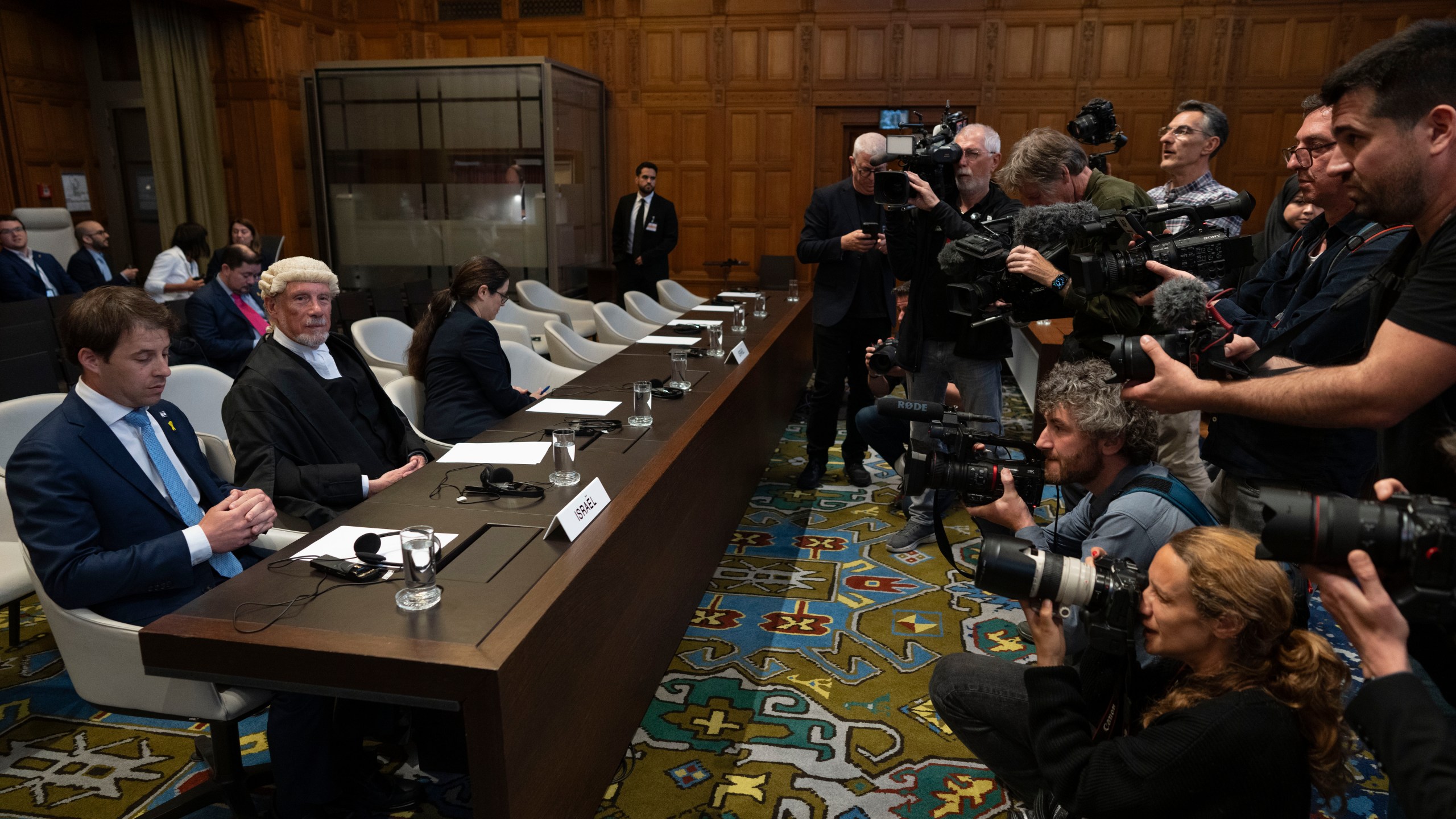 Journalists take images of Israel legal team before Judges enter the International Court of Justice, or World Court, in The Hague, Netherlands, Friday, May 24, 2024, where the top United Nations court ruled on an urgent plea by South Africa for judges to order Israel to halt its military operations in Gaza and withdraw from the enclave. (AP Photo/Peter Dejong)