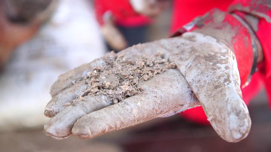 A hand holding sandy debris.