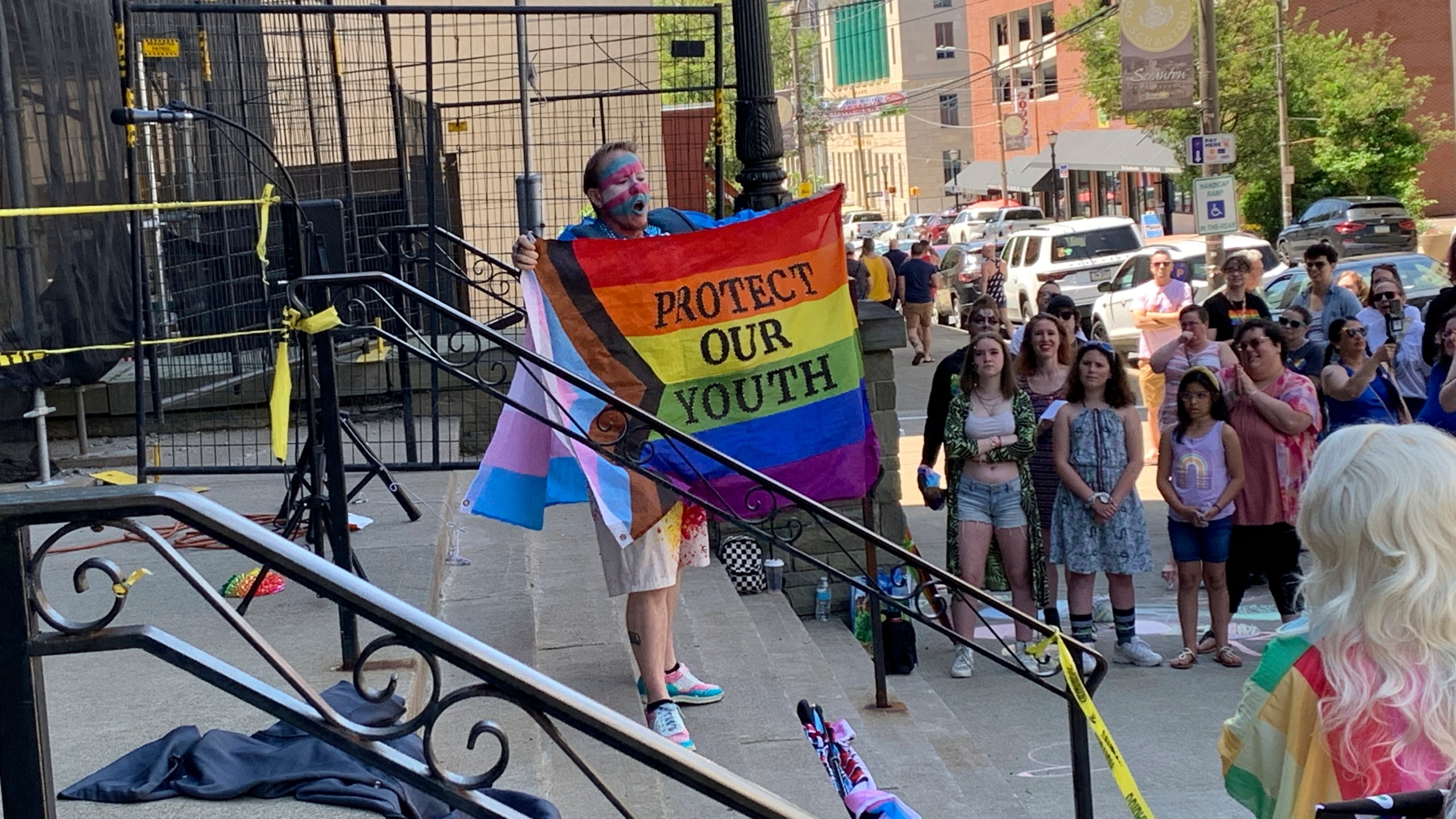 A performer advocates for LGBTQ+ youth on the steps of Scranton City Hall Saturday, June 1, 2024, in Scranton, Pa. Pride Month is kicking off around the world with parades and festivals in cities large and small. The annual celebrations of LGBTQ+ people and culture began Saturday against a complicated backdrop of backlashes. (AP Photo/Jeff McMillan)