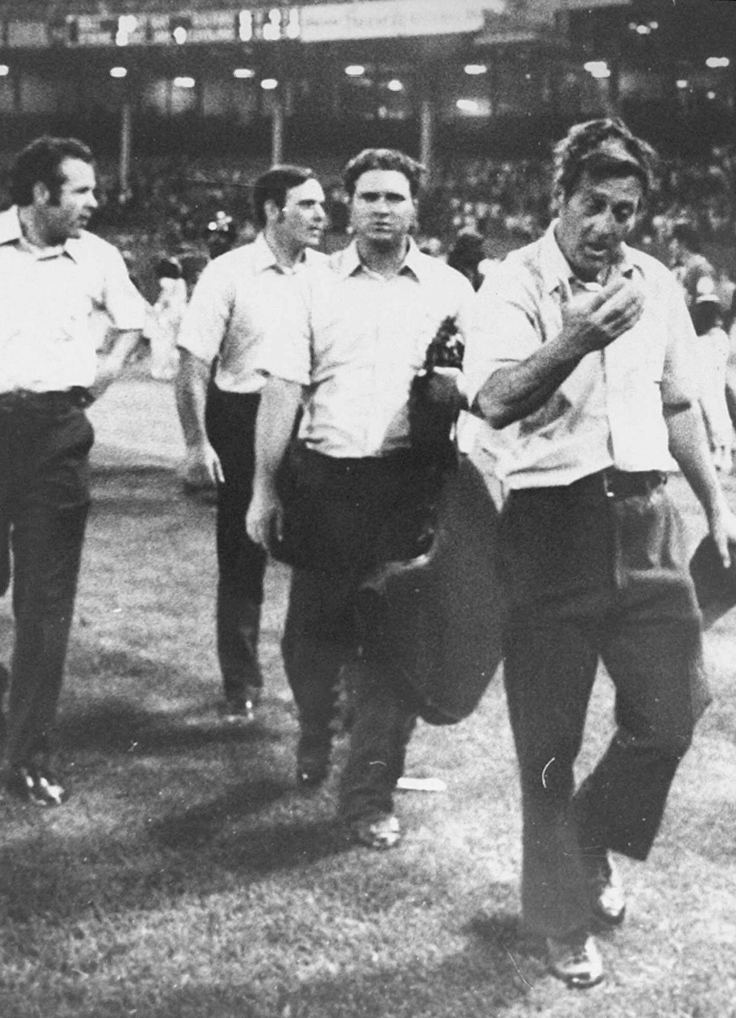 FILE - In this image provided by Special Collections, Cleveland State University, injured umpire Nestor Chylak, right, leads his crew, from left, Joe Brinkman, Nick Bremigan, and Larry McCoy off the field during the Beer Night melee at Cleveland Stadium, June 4, 1974, in Cleveland. The Cleveland Indians forfeited the baseball game to the Rangers after fans, fueled by 10-cent beers, stormed the field in the ninth inning. (Paul Tepley/Cleveland Press, Special Collections, Cleveland State University, via AP, File)