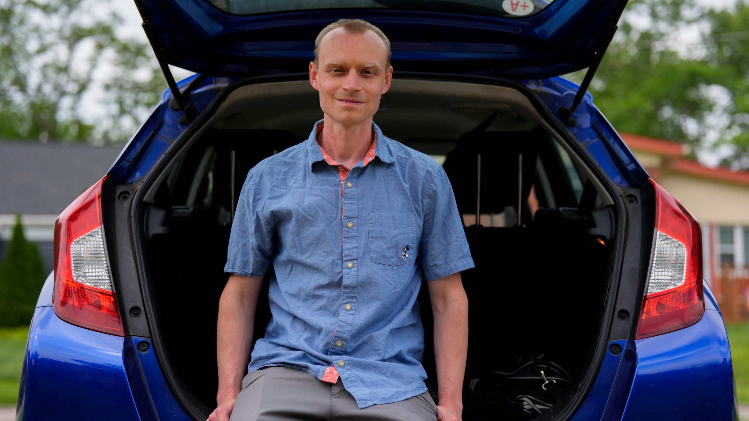 Caleb Jud, 33, poses for a portrait with his Honda Fit, Monday, May 13, 2024, in Cincinnati. Many Americans still aren’t sold on going electric for their next car purchase. High prices and a lack of easy-to-find charging stations are major sticking points, a new poll shows. Jud said he’s considering an EV, but may end up with a plug-in hybrid — if he goes electric. (AP Photo/Joshua A. Bickel)