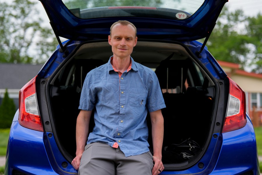 Caleb Jud, 33, poses for a portrait with his Honda Fit, Monday, May 13, 2024, in Cincinnati. Many Americans still aren’t sold on going electric for their next car purchase. High prices and a lack of easy-to-find charging stations are major sticking points, a new poll shows. Jud said he’s considering an EV, but may end up with a plug-in hybrid — if he goes electric. (AP Photo/Joshua A. Bickel)