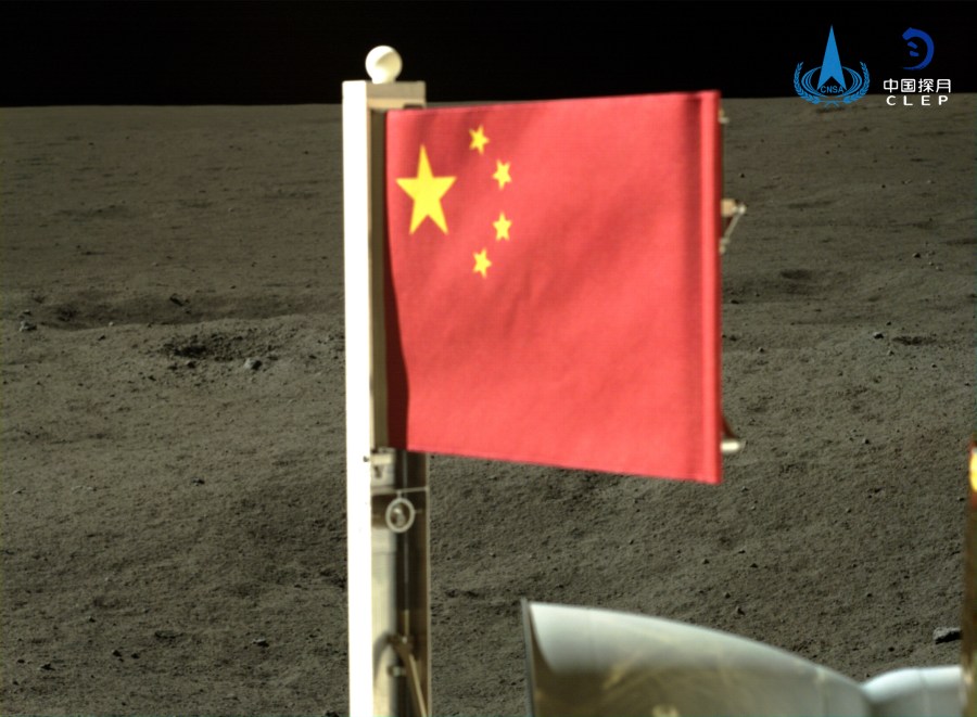 In this China National Space Administration (CNSA) handout image released by Xinhua News Agency, a Chinese national flag carried by the lander of Chang'e-6 probe unfurls at the moon's far side, Tuesday, June 4, 2024. China says a spacecraft carrying rock and soil samples from the far side of the moon has lifted off from the lunar surface to start its journey back to Earth. (CNSA/Xinhua via AP)