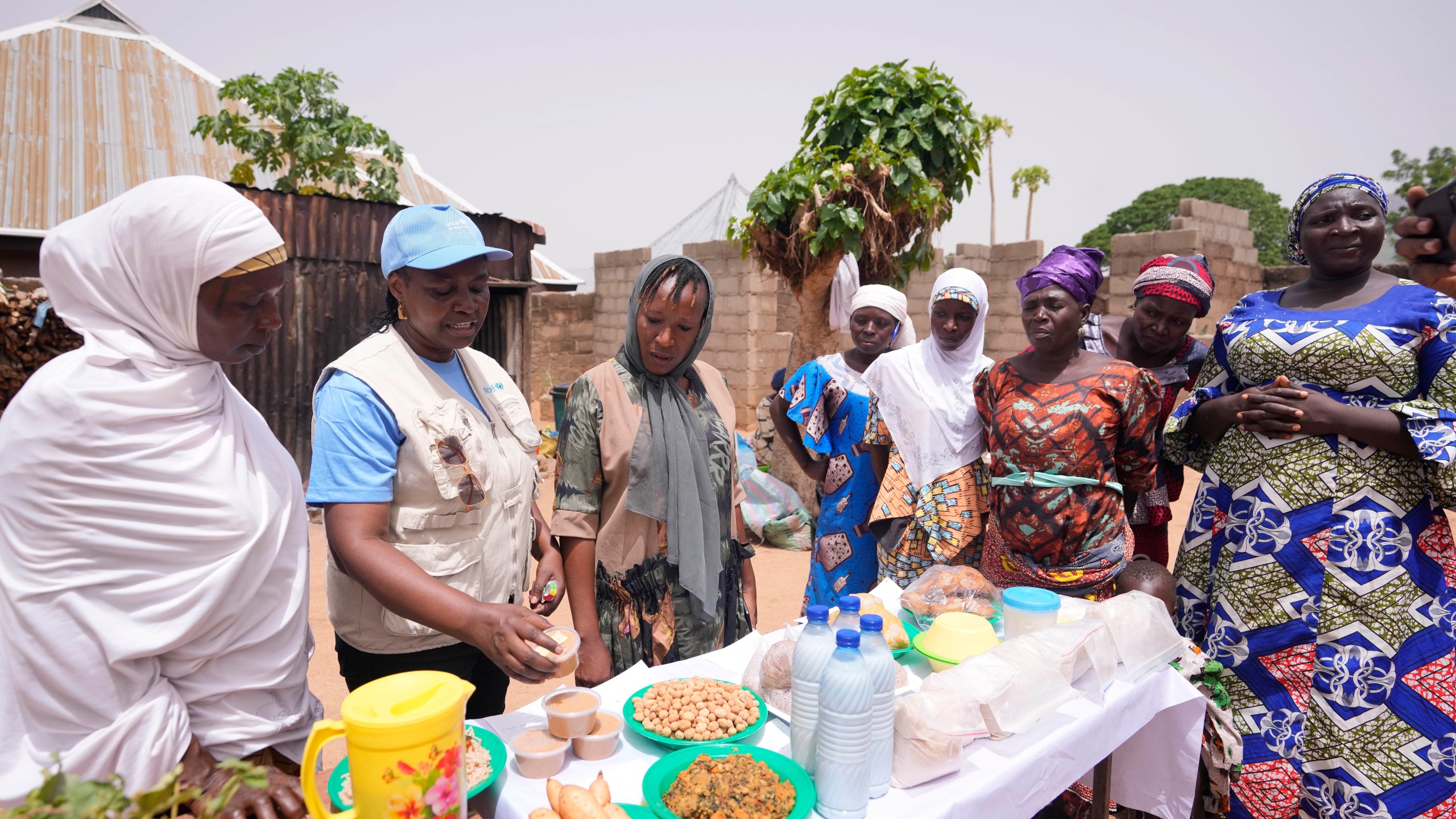 Philomena Irene, UNICEF Nutrition specialist, speaks to women about food that will boost their families' nutrient intake with tubers and grains like cassava, orange-fleshed sweet potato, in Kaltungo Poshereng Nigeria, Sunday, June 2, 2024. More than a dozen women gathered this week in Kaltungo's Poshereng village where they are learning at least 200 recipes they can prepare with those local foods which, in the absence of rain, are grown in sand-filled sacks that require small amounts of water. The training session mirrored the struggles of households who are more challenged amid Nigeria's worst cost of living crisis. (AP Photo/Sunday Alamba)