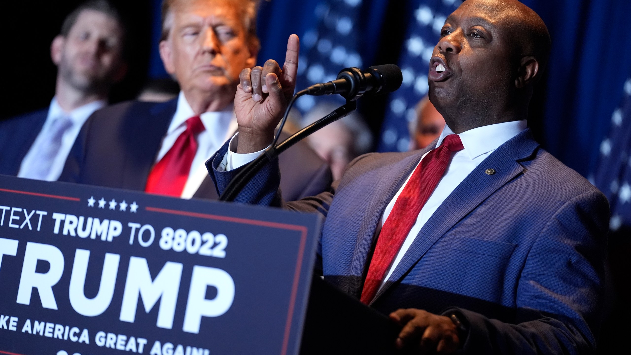 FILE - Republican presidential candidate former President Donald Trump listens as Sen. Tim Scott, R-S.C., speaks at a primary election night party at the South Carolina State Fairgrounds in Columbia, S.C., Saturday, Feb. 24, 2024. A top ally of former President Donald Trump — and a potential running mate — is launching a new effort to win over Black and other nonwhite working class voters he argues could be the deciding factor in November's elections. South Carolina Sen. Tim Scott, the only Black Republican in the Senate, will lead a $14 million campaign targeting minority voters in seven key swing states. (AP Photo/Andrew Harnik, File)