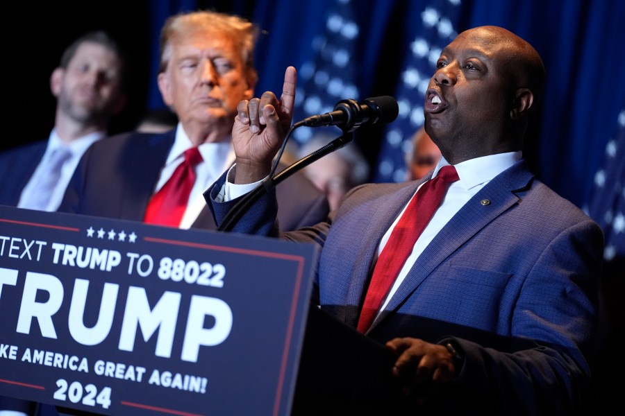 FILE - Republican presidential candidate former President Donald Trump listens as Sen. Tim Scott, R-S.C., speaks at a primary election night party at the South Carolina State Fairgrounds in Columbia, S.C., Saturday, Feb. 24, 2024. A top ally of former President Donald Trump — and a potential running mate — is launching a new effort to win over Black and other nonwhite working class voters he argues could be the deciding factor in November's elections. South Carolina Sen. Tim Scott, the only Black Republican in the Senate, will lead a $14 million campaign targeting minority voters in seven key swing states. (AP Photo/Andrew Harnik, File)