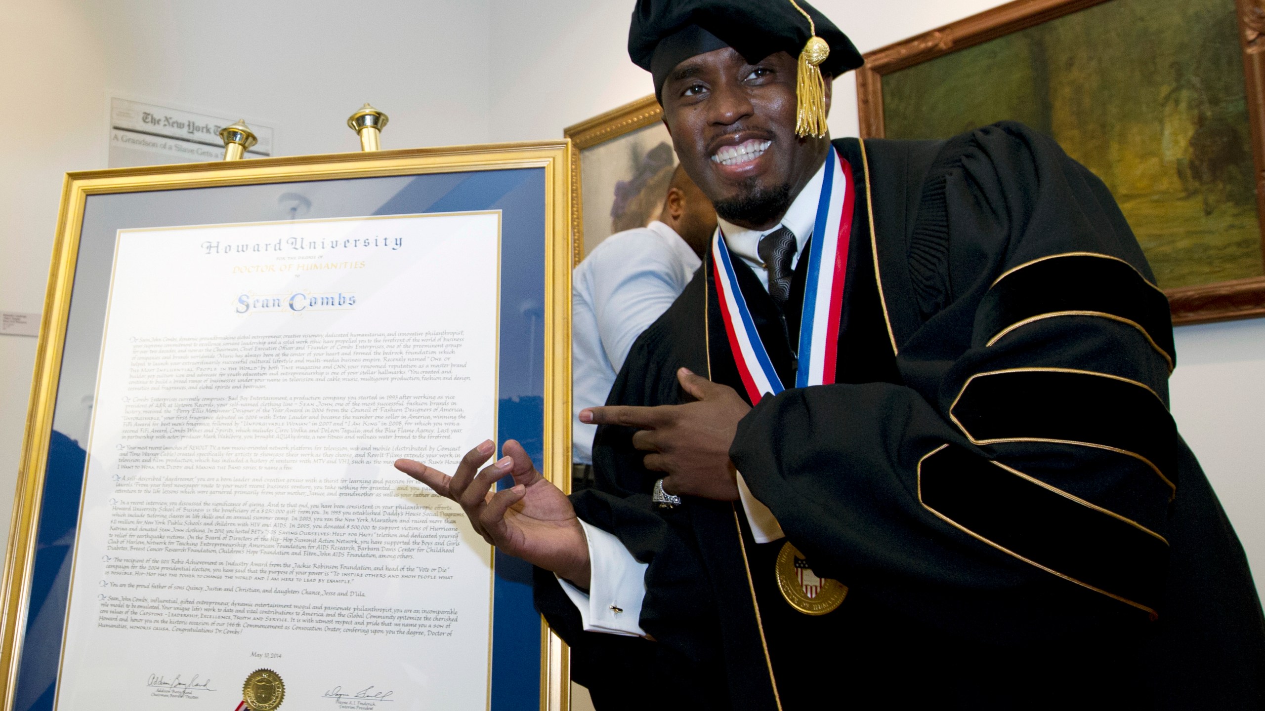 FILE - Entertainer and entrepreneur Sean Combs poses next to his honorary degree of Doctor of Humanities during the graduation ceremony at Howard University in Washington, Saturday, May 10, 2014. In a decision, Friday, June 7, 2024, Howard University is cutting ties to Combs, rescinding the honorary degree that was awarded to him and disbanding a scholarship program in his name. (AP Photo/Jose Luis Magana, File)