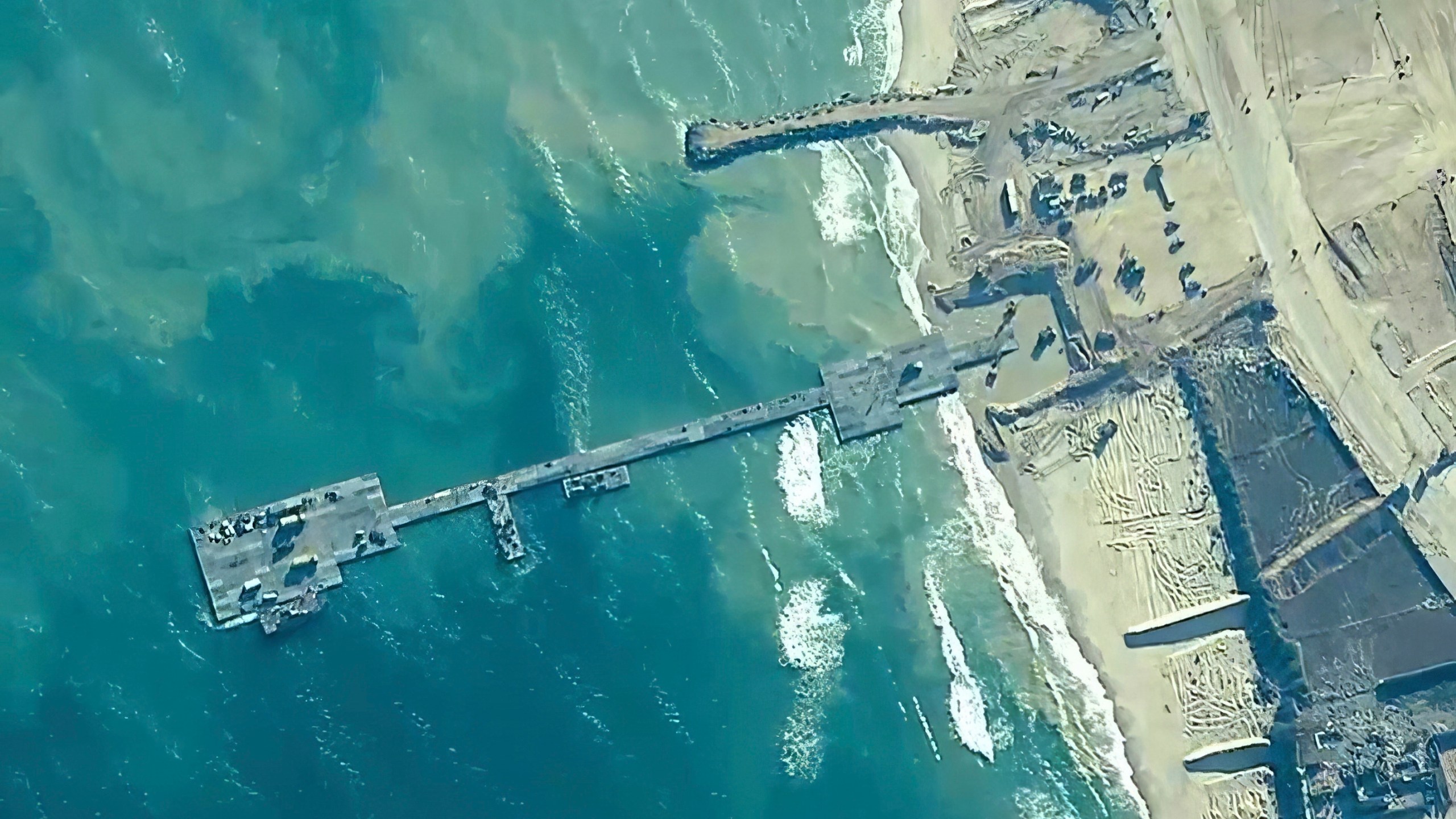 FILE - The image provided by U.S, Central Command, shows U.S. Army soldiers assigned to the 7th Transportation Brigade (Expeditionary), U.S. Navy sailors assigned to Amphibious Construction Battalion 1, and Israel Defense Forces placing the Trident Pier on the coast of Gaza Strip on May 16, 2024. A key section of the U.S. military-built pier designed to carry badly needed aid into Gaza by boat has been reconnected to the Gaza beach following storm damage repairs and aid will begin to flow soon, the U.S. Central Command announced Friday. (U.S. Central Command via AP)