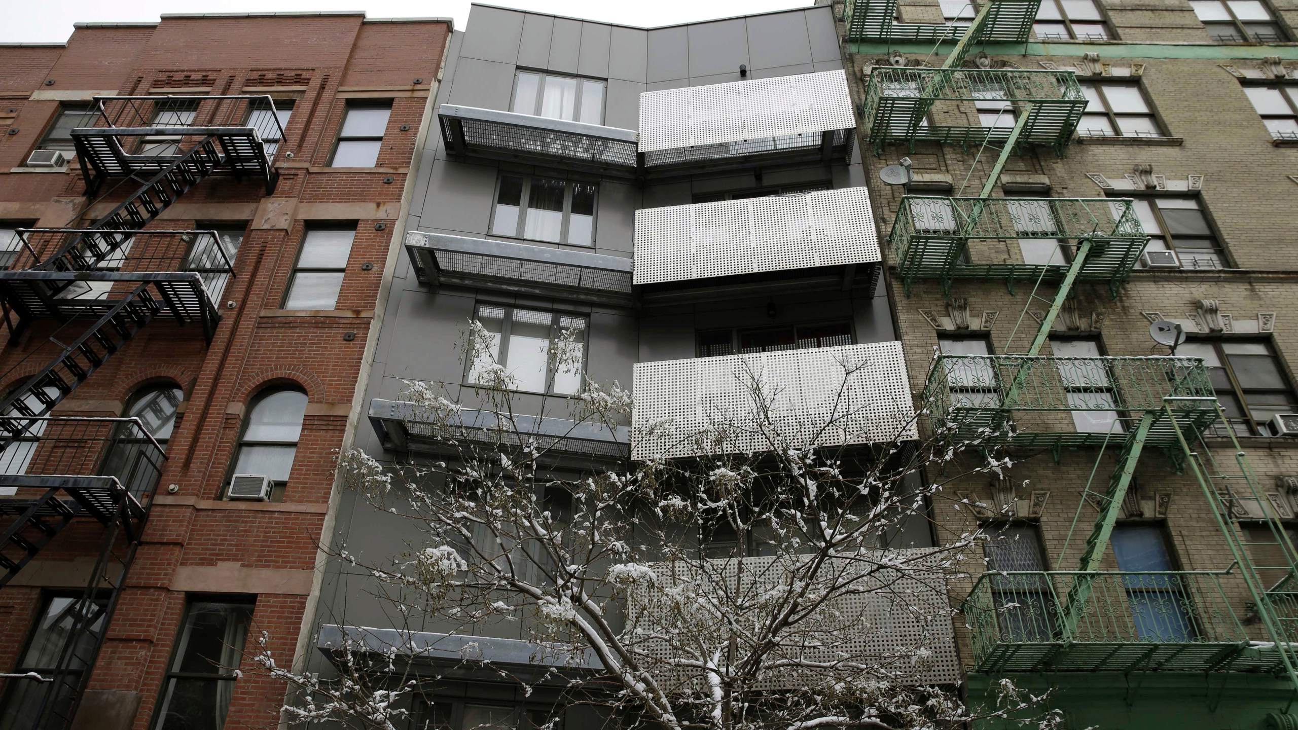 FILE - A new building sits between two older-style buildings in the East Harlem section of New York, Feb. 3, 2015. Legislation backed by a majority of the New York City Council would require landlords who hire brokers to pay their broker fees, marking a potential sea change in one of the country’s most expensive housing markets. (AP Photo/Seth Wenig, File)