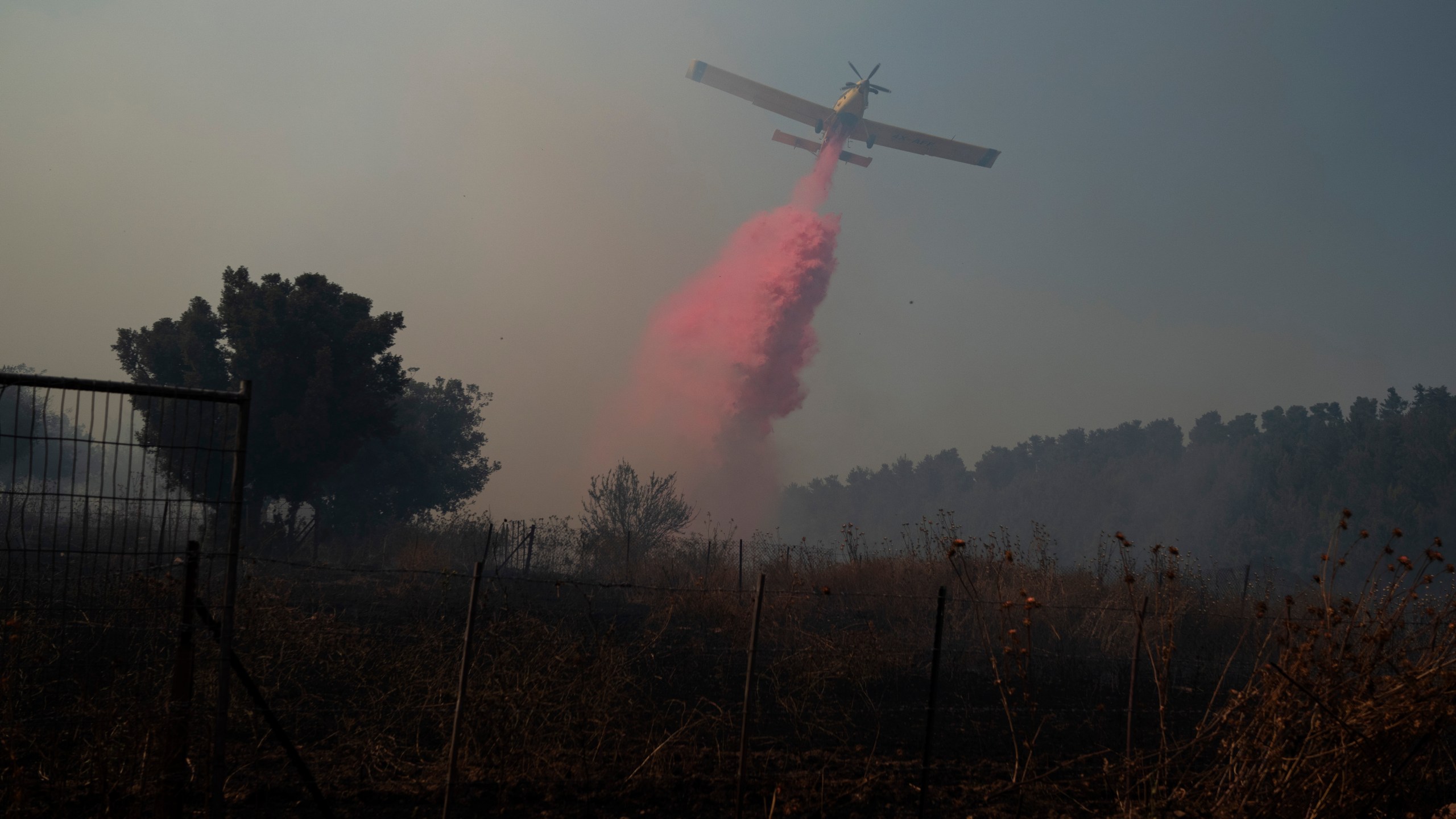 A plane uses a fire retardant to extinguish a fire burning in an area near the border with Lebanon, in Safed, northern Israel, Wednesday, June 12, 2024. Scores of rockets were fired from Lebanon toward northern Israel on Wednesday morning, hours after Israeli airstrikes killed four officials from the militant Hezbollah group including a senior military commander. (AP Photo/Leo Correa)