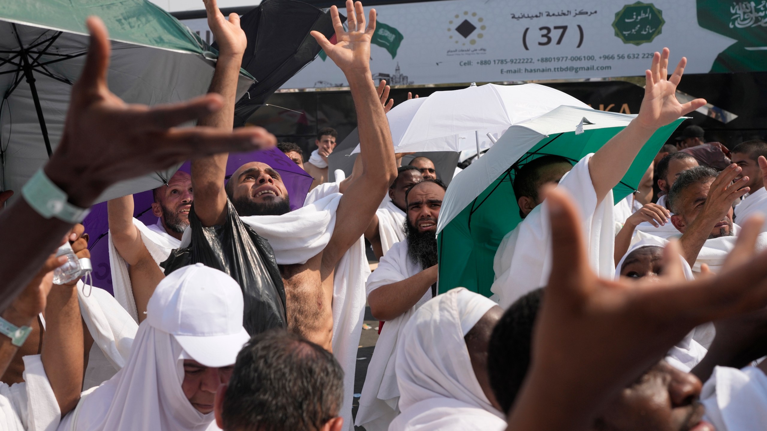 Muslim pilgrims try to reach for free drinking water being distributed in Arafat, on the second day of the annual hajj pilgrimage, near the holy city of Mecca, Saudi Arabia, Saturday, June 15, 2024. Masses of Muslims gathered at the sacred hill of Mount Arafat in Saudi Arabia for worship and reflection on the second day of the Hajj pilgrimage. (AP Photo/Rafiq Maqbool)