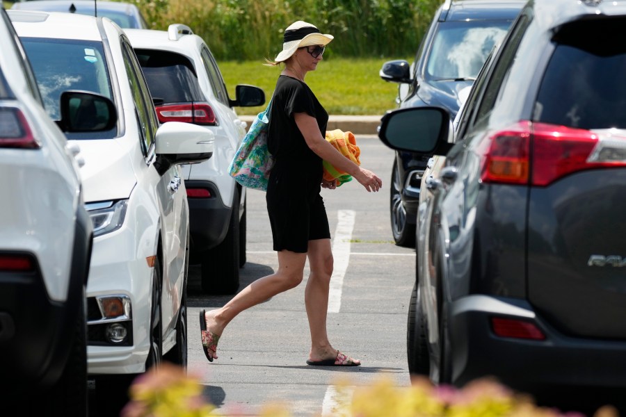 A woman walks in parking lot area at Heritage Park during hot weather in Riverwoods, Ill., Monday, June 17, 2024. (AP Photo/Nam Y. Huh)