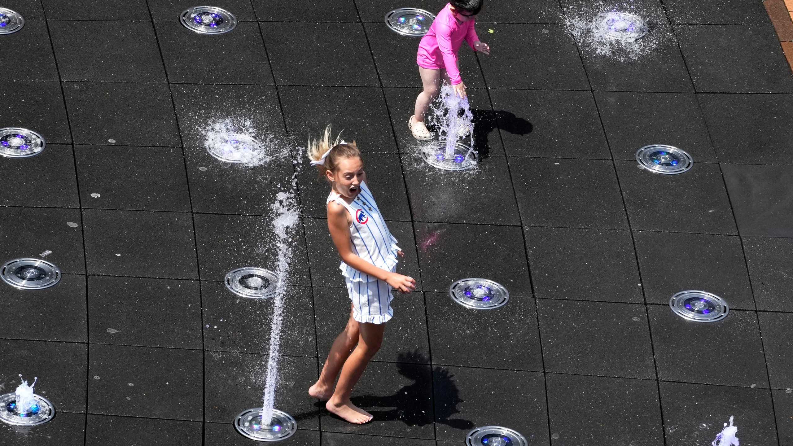 Kids cool off at Gallagher Way park fountain during hot weather in Chicago, Sunday, June 16, 2024. (AP Photo/Nam Y. Huh)