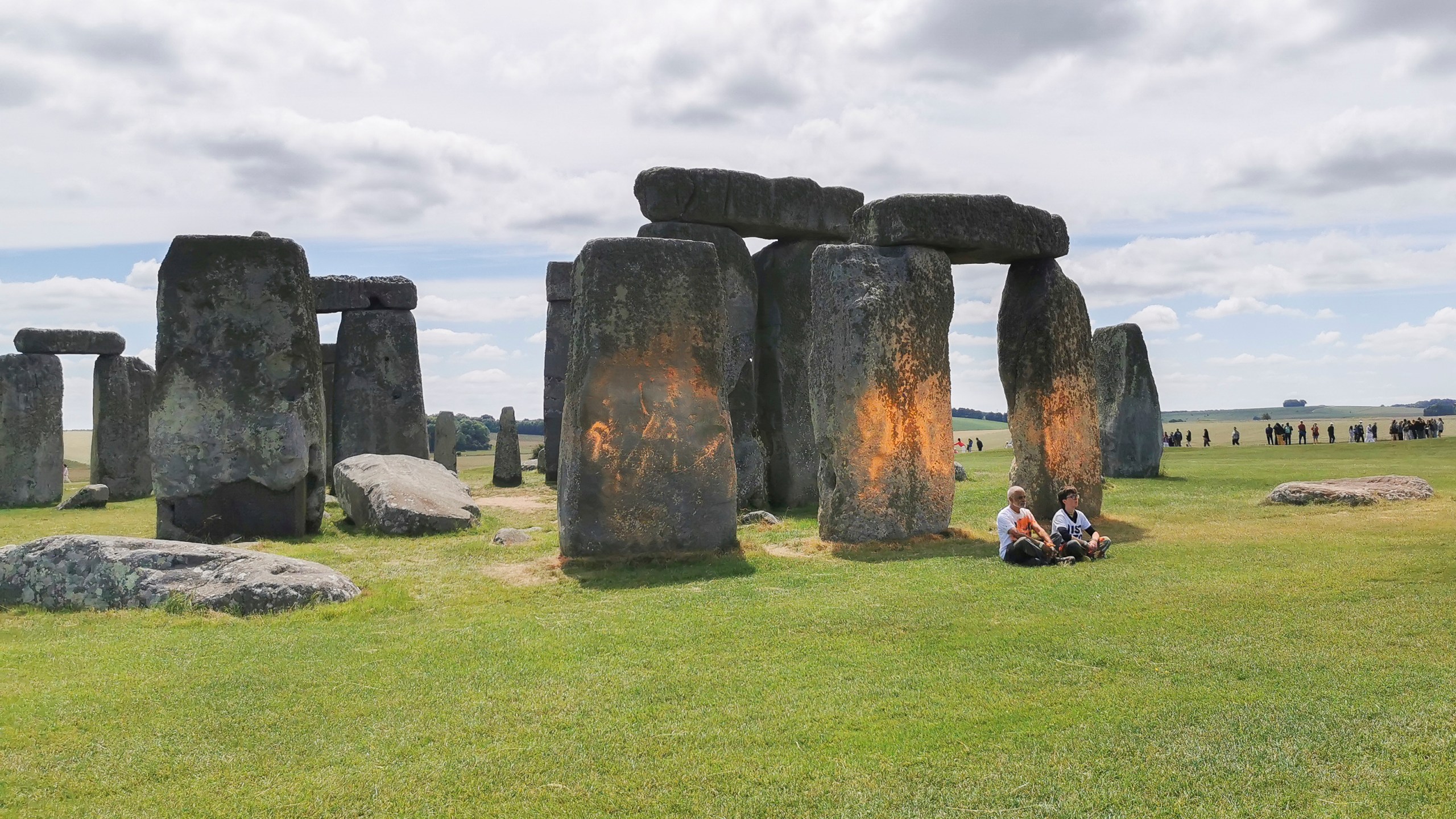 In this handout photo, Just Stop Oil protesters sit after spraying an orange substance on Stonehenge, in Salisbury, England, Wednesday June 19, 2024. (Just Stop Oil via AP)