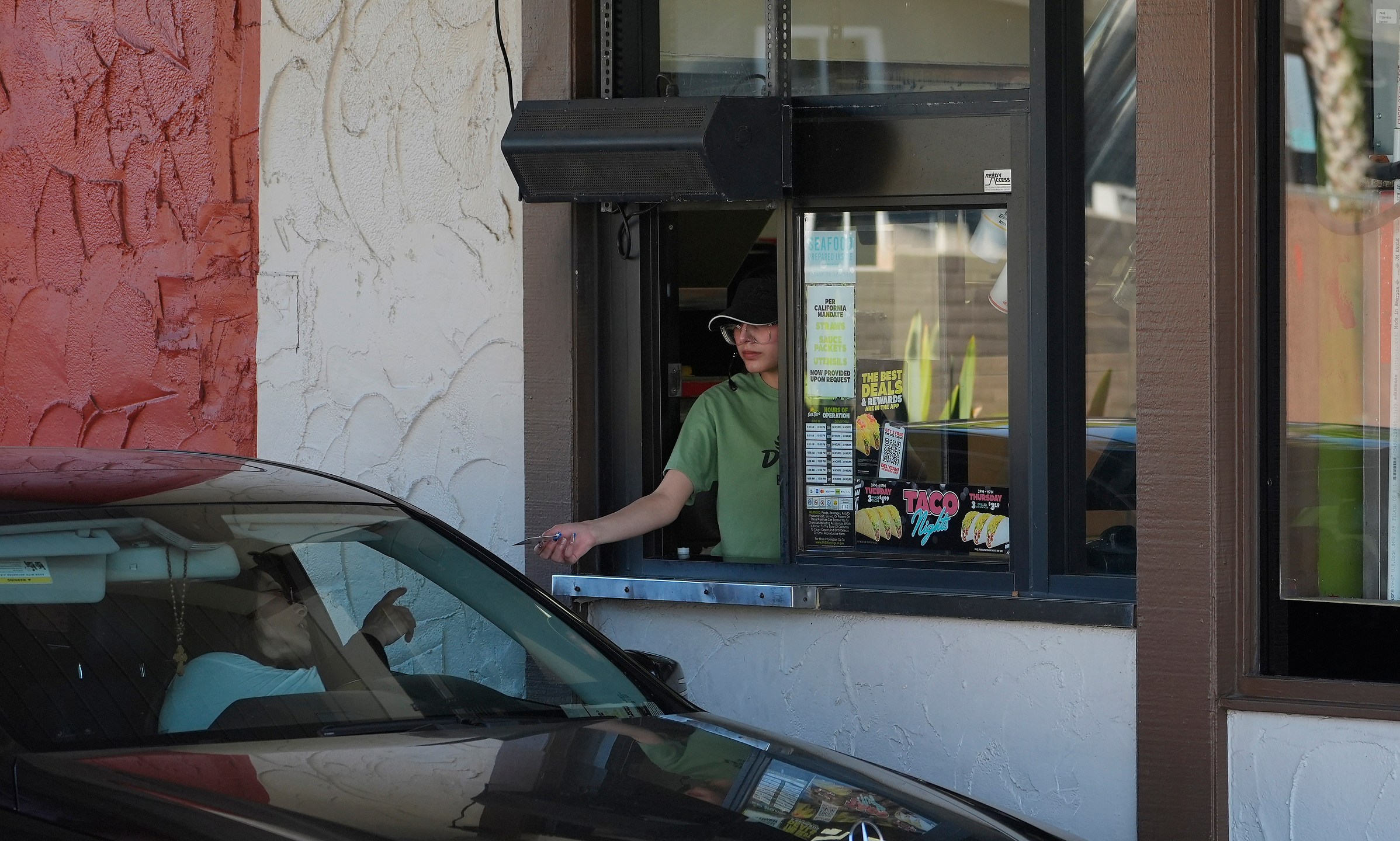 FILE - A customer pays for their food at the drive-thru of a fast-food restaurant in Los Angeles, April 1, 2024. California’s workplace regulators passed rules that would protect indoor workers from extreme heat. (AP Photo/Damian Dovarganes, File)