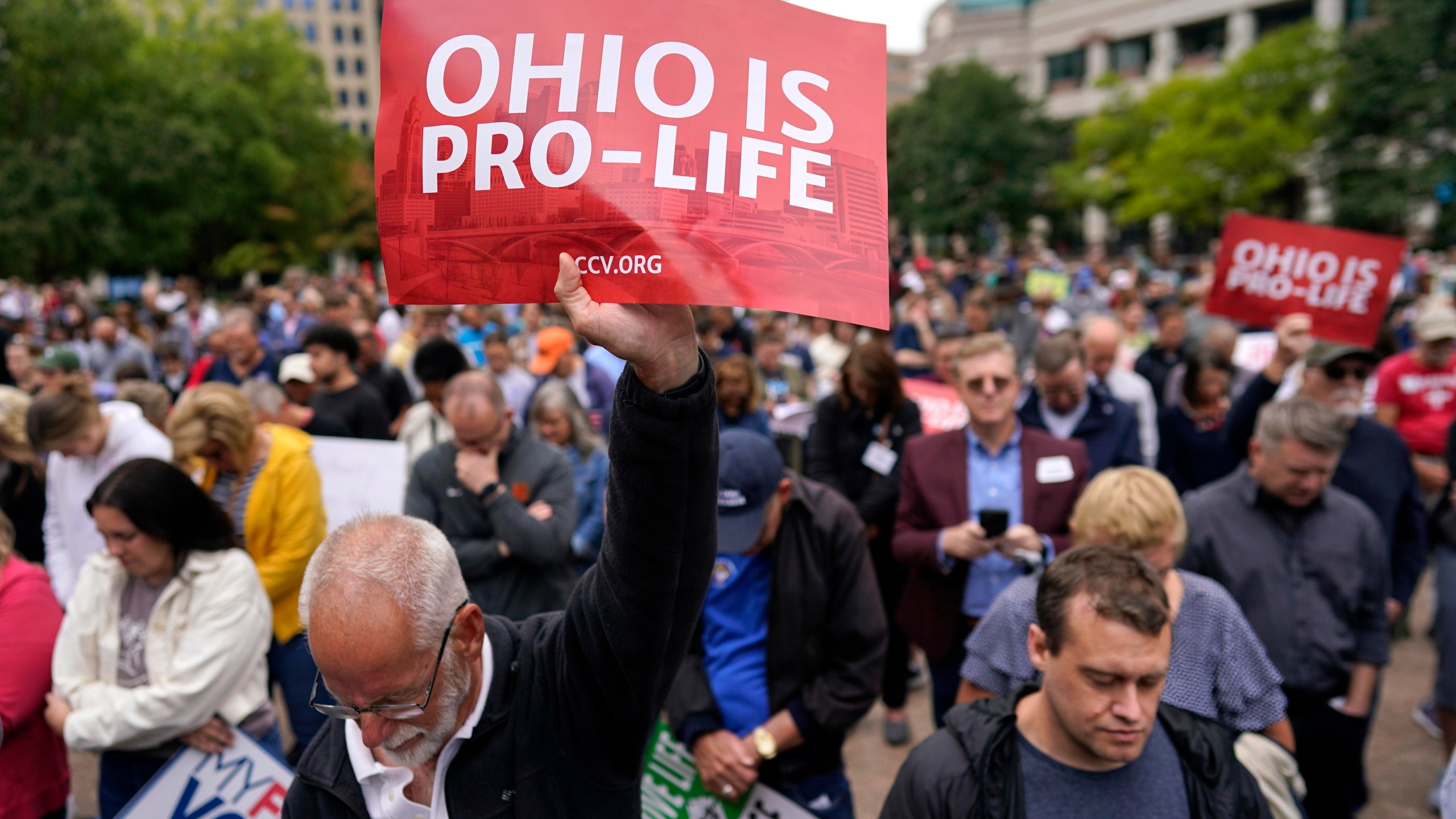 FILE - Paul Meacham holds high a sign that reads "Ohio is pro-life" as the crowd prays during the Ohio March for Life rally at the Ohio State House in Columbus, Ohio, Friday, Oct. 6, 2023. Two years after the U.S. Supreme Court ended a nationwide right to abortion, travel and pills have become big parts of the issue. (AP Photo/Carolyn Kaster, File)