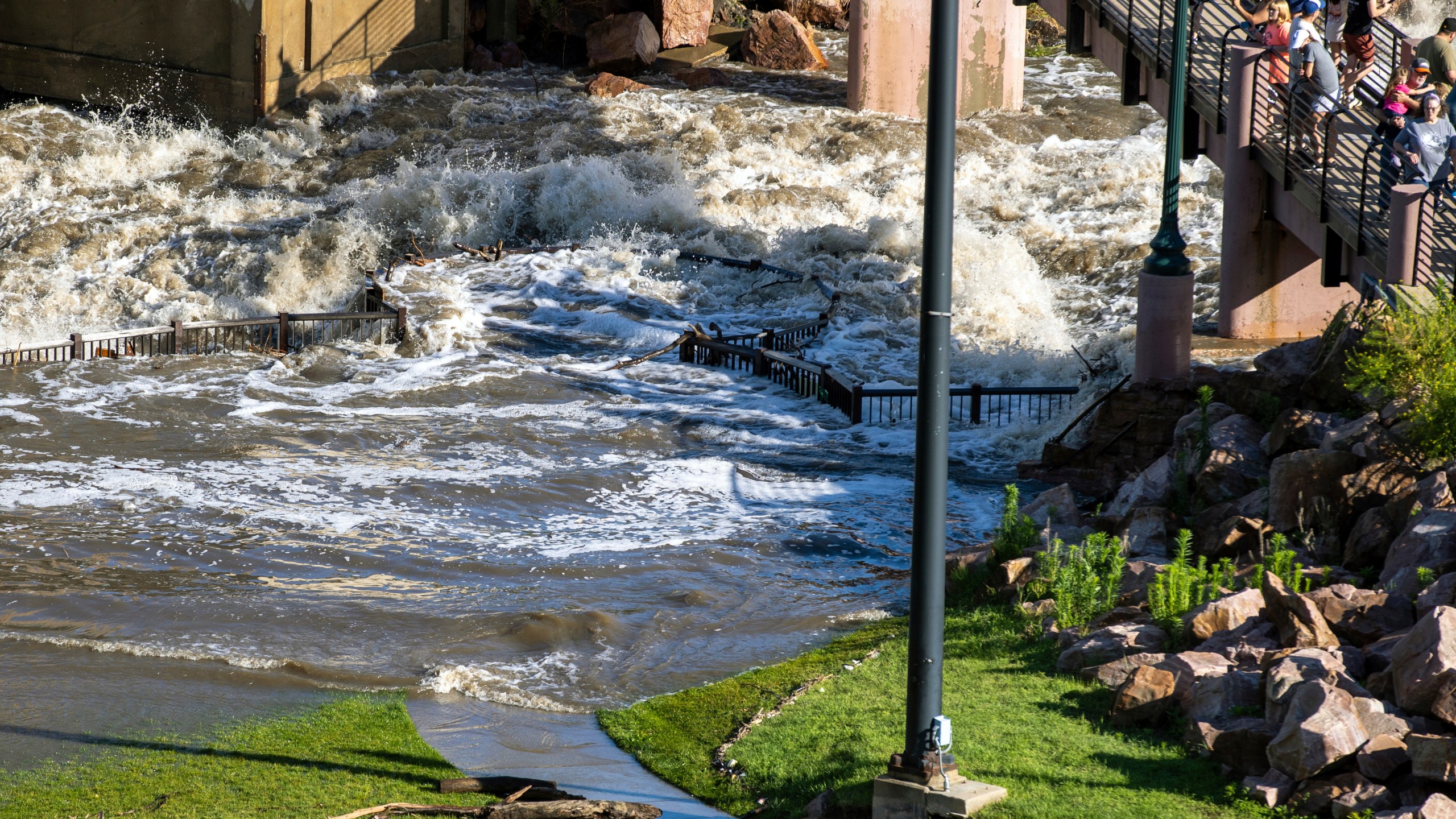 People on a viewing platform watch as Falls Park in Sioux Falls, S.D, was underwater on Saturday, June 22, 2024, after days of heavy rain led to flooding in the area. (AP Photo/Josh Jurgens)