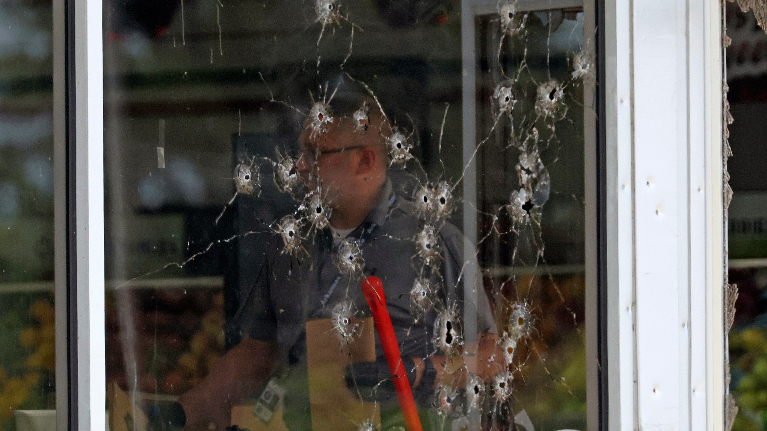 Damage can be seen to a front window law enforcement officers work the scene of a shooting at the Mad Butcher grocery store in Fordyce, Ark., Friday, June 21, 2024. (Colin Murphey/Arkansas Democrat-Gazette via AP)