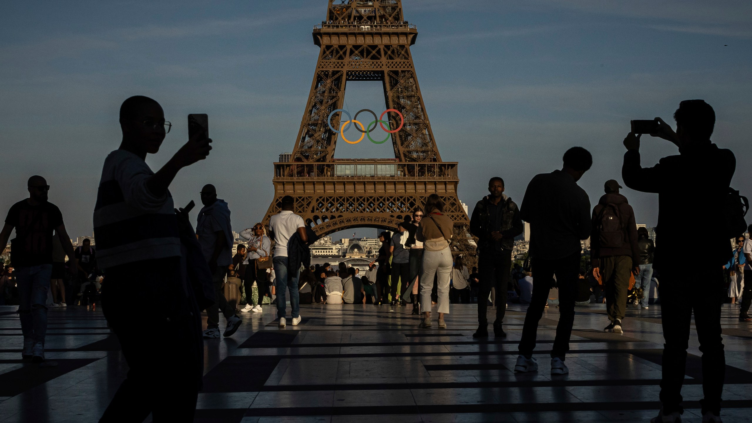 FILE - People film the Olympic rings that are displayed on the Eiffel Tower, June 7, 2024 in Paris. On Wednesday, 26, 2024, NBC announced plans to change the way they cover the 2024 Olympics. (AP Photo/Aurelien Morissard, File)