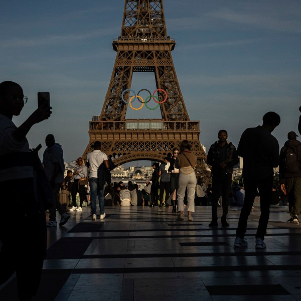 FILE - People film the Olympic rings that are displayed on the Eiffel Tower, June 7, 2024 in Paris. On Wednesday, 26, 2024, NBC announced plans to change the way they cover the 2024 Olympics. (AP Photo/Aurelien Morissard, File)