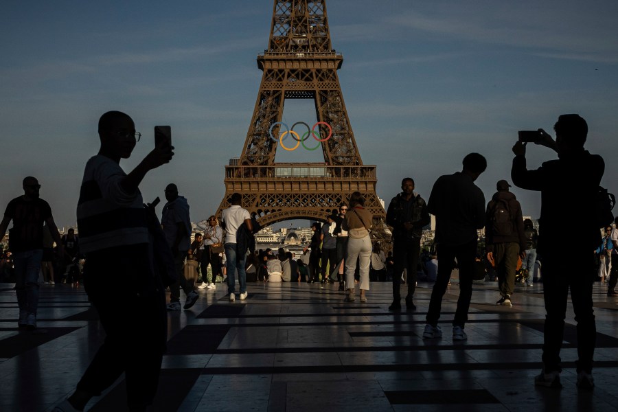 FILE - People film the Olympic rings that are displayed on the Eiffel Tower, June 7, 2024 in Paris. On Wednesday, 26, 2024, NBC announced plans to change the way they cover the 2024 Olympics. (AP Photo/Aurelien Morissard, File)