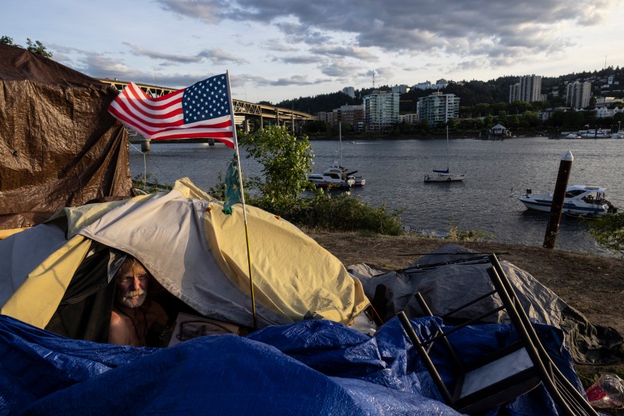 FILE - Frank, a homeless man, sits in his tent with a river view, June 5, 2021, in Portland, Ore. The Supreme Court ruled on Friday, June 28, 2024, that cities can enforce bans on homeless people sleeping outdoors in West Coast areas where shelter space is lacking. (AP Photo/Paula Bronstein, File)