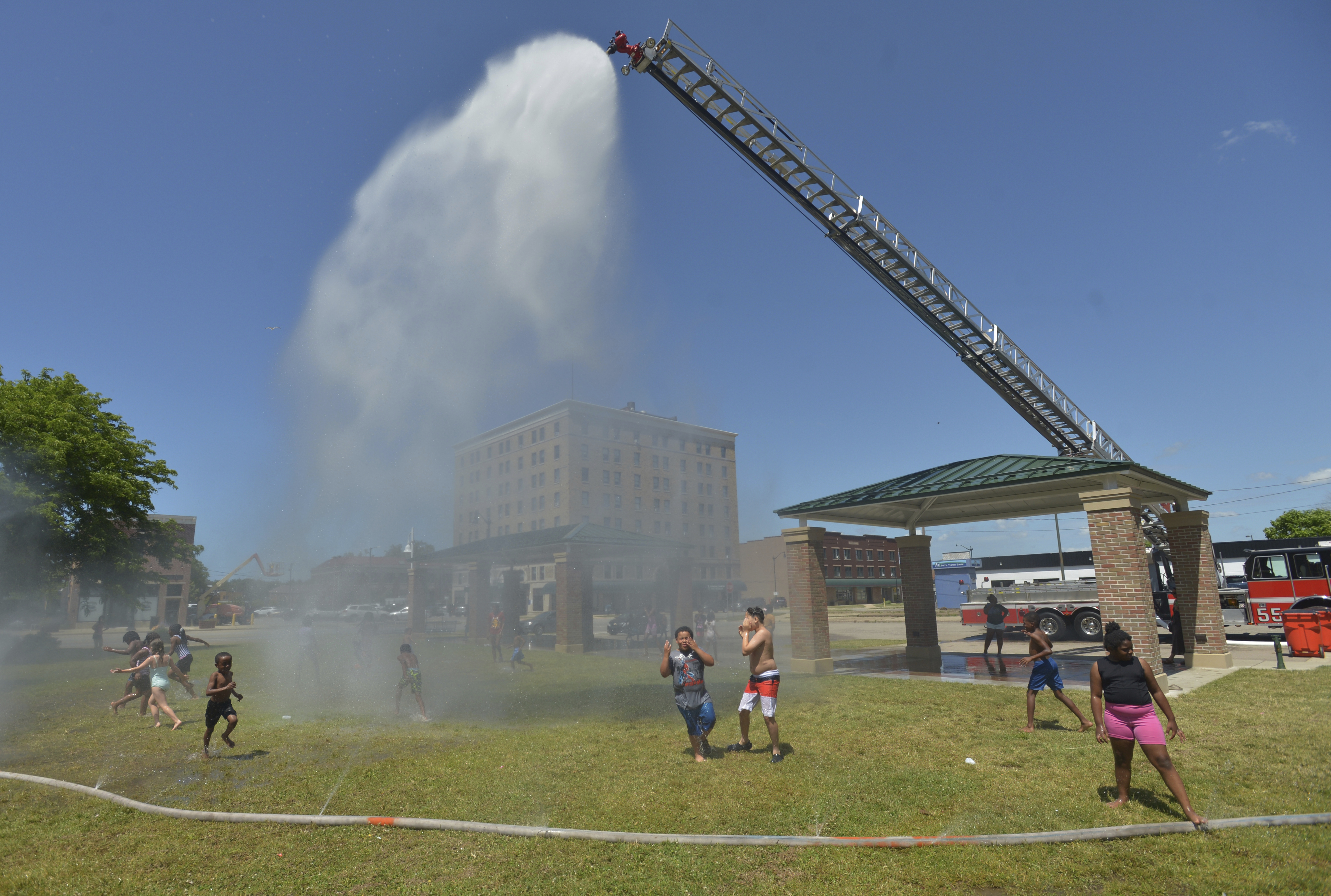 Children run through water sprayed by the fire department in Harbor, Michigan on June 18, 2024.