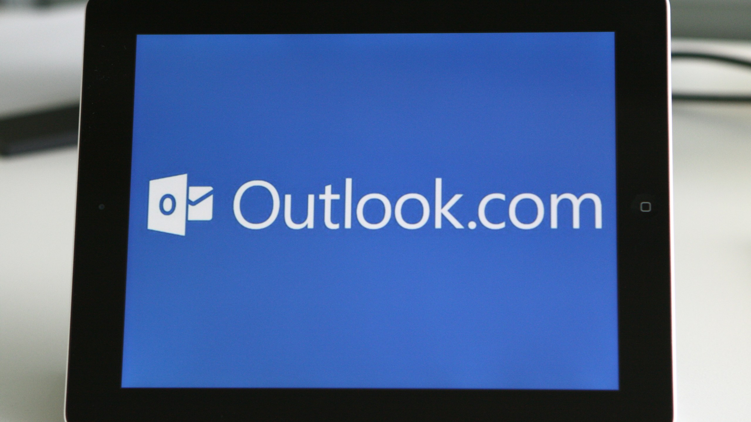 The logo of the personal information manager Outlook is visible on a tablet computer.