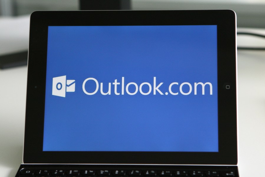 The logo of the personal information manager Outlook is visible on a tablet computer.