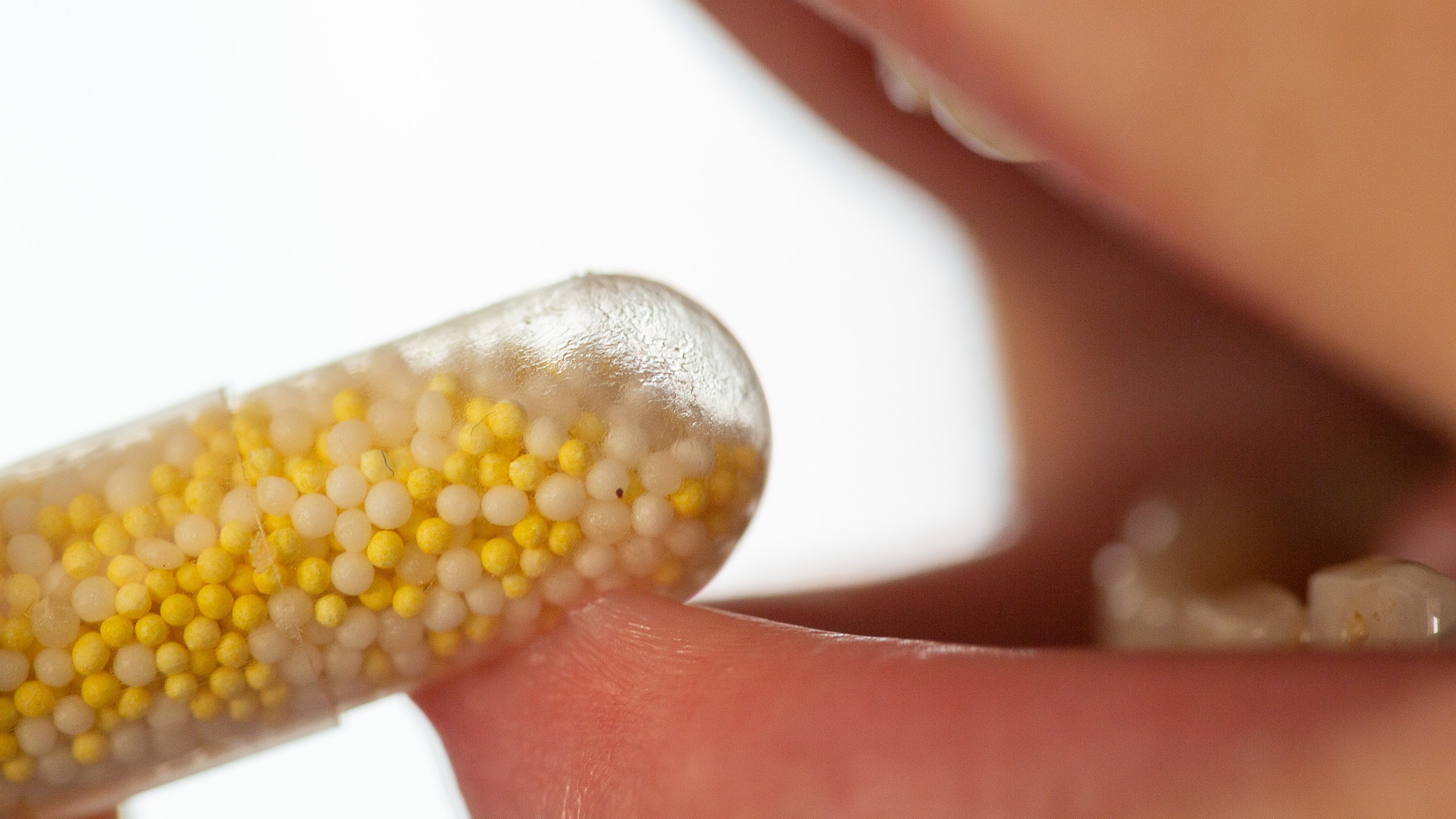 A person takes a capsule containing a dietary supplement with potassium and magnesium.