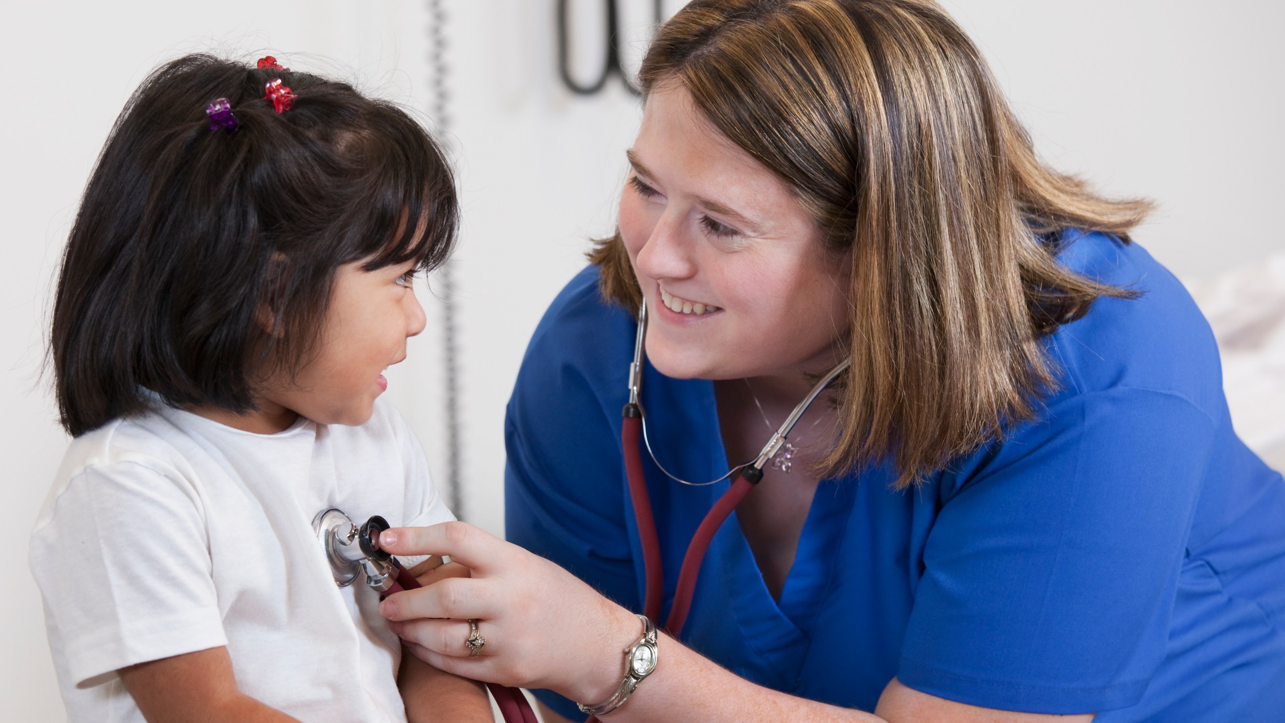 Doctor listening to girl's breathing in doctor's office