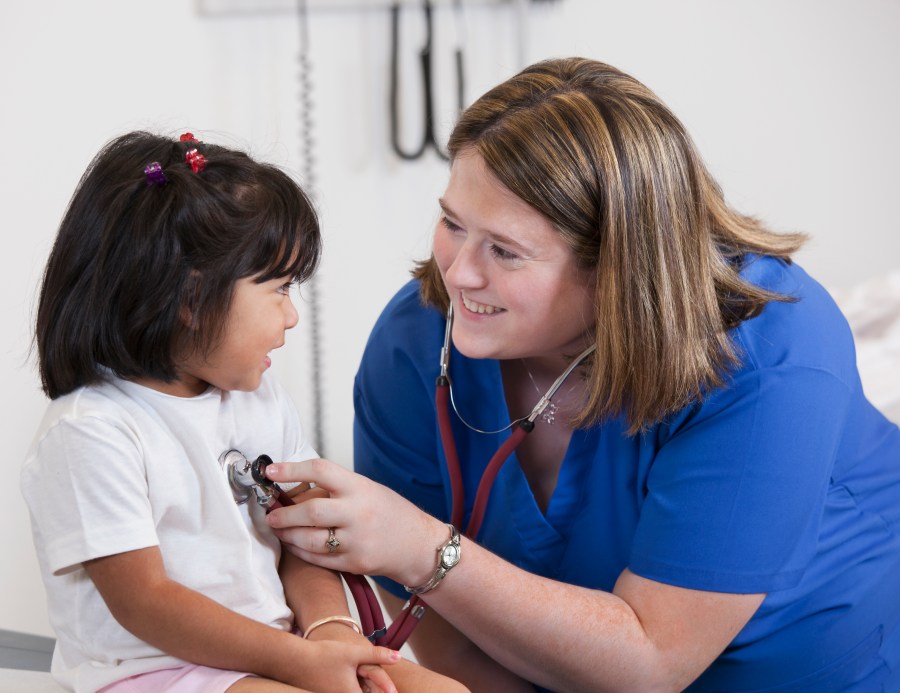 Doctor listening to girl's breathing in doctor's office