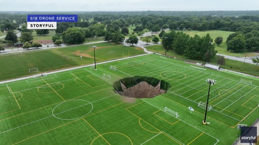 A large sinkhole in the middle of a recreational field.