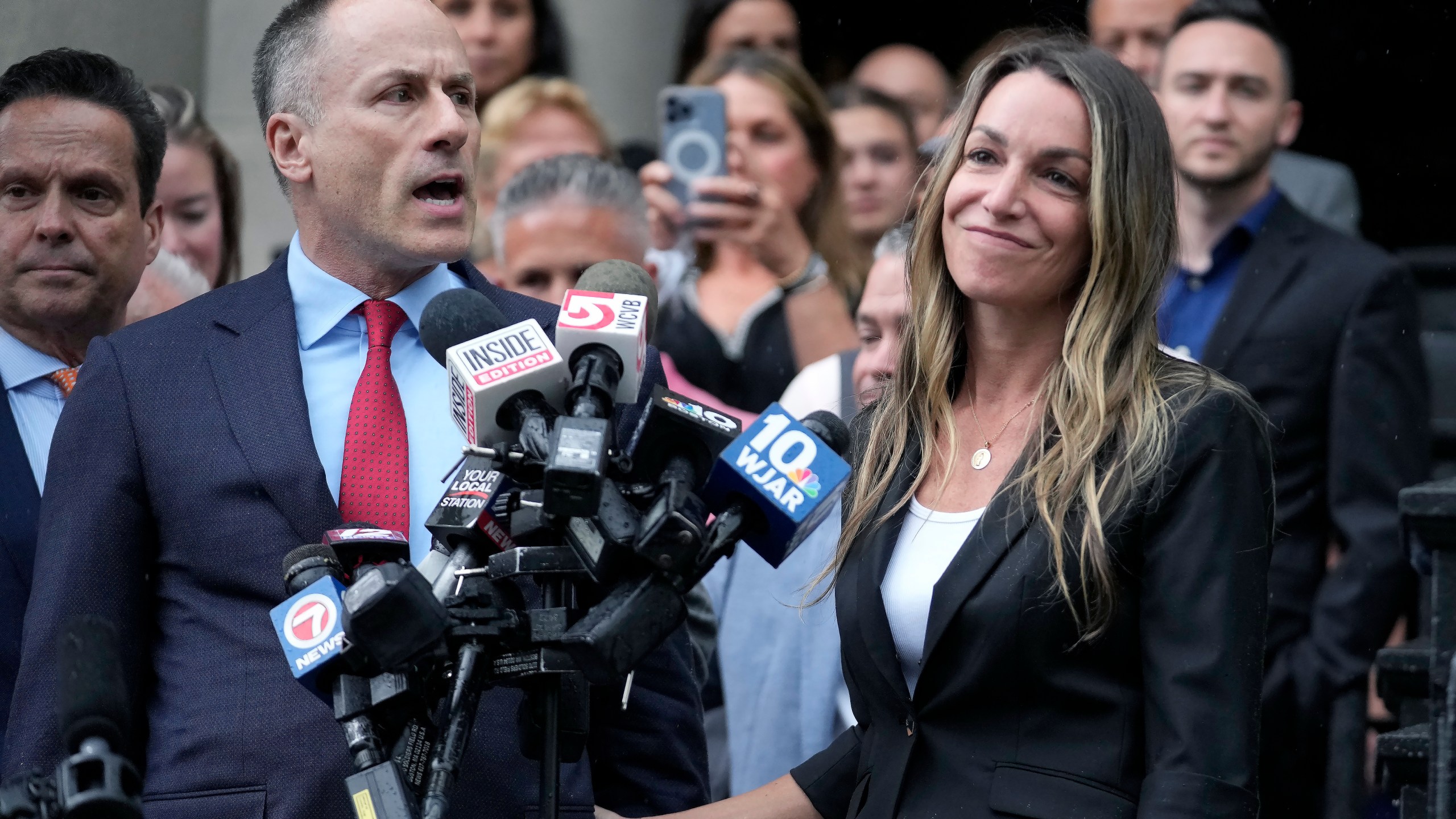 Karen Read, right, smiles as defense attorney David Yannetti, front left, speaks to reporters in front of Norfolk Superior Court after the judge declared a mistrial after jurors were unable to reach a verdict following a two-month trial, Monday, July 1, 2024, in Dedham, Mass. (AP Photo/Steven Senne)