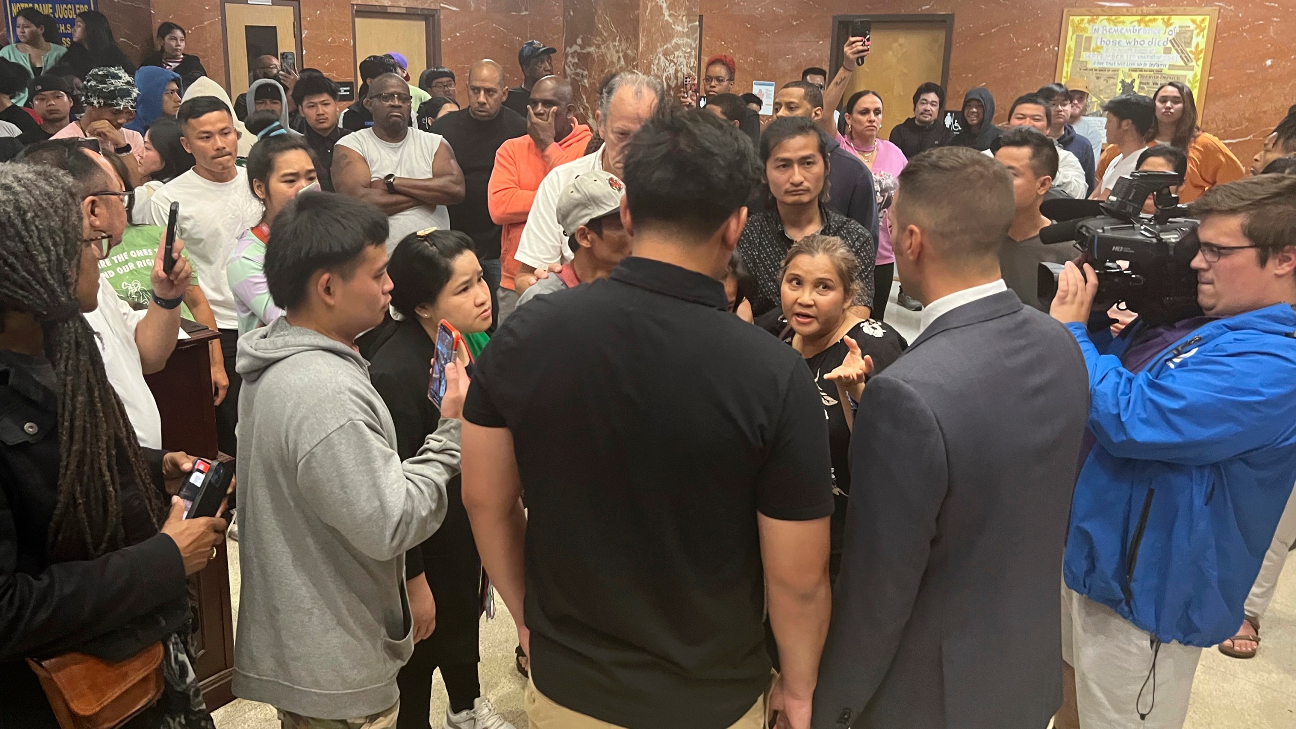 Utica Mayor Michael Galime, center right, grey jacket, talks with the family members of a 13-year-old boy who was fatally shot by a police officer Friday night after a news conference, Saturday, June 28, 2024 in Utica, N.Y. An officer shot and killed the teenager who was fleeing while wielding a “realistic appearing firearm," authorities said Saturday. (Kenny Lacy Jr./Syracuse.com via AP)