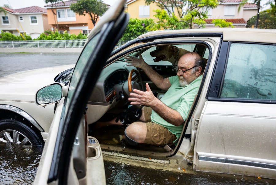 FILE - Mike Viesel and his dog Humi, wait in his flooded car for a tow, June 12, 2024, in Hollywood, Fla. Unlike previous hurricane seasons, this summer brings record hot temperatures nationwide and an early onset of storms. Hurricane season runs June 1 to Nov. 30, but usually the months where most hurricanes have occurred are September and October, said Jaime Hernandez, the emergency management director for Hollywood, on Florida's Atlantic Coast. (Matias J. Ocner/Miami Herald via AP, File)