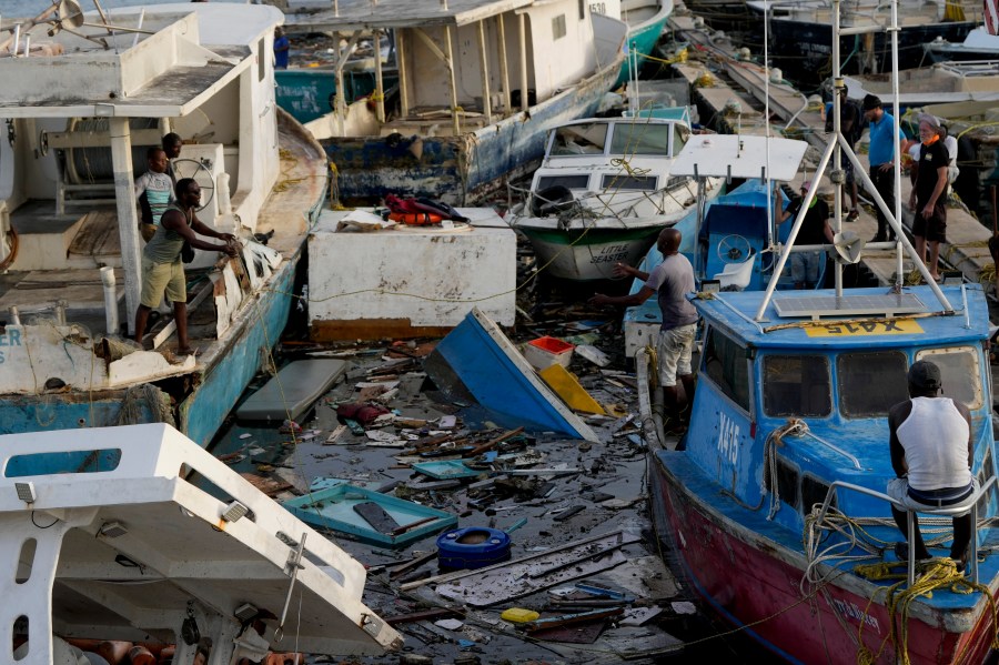 A fisherman throws a rope across boats damaged by Hurricane Beryl at Bridgetown Fisheries, Barbados, Tuesday, July 2, 2024. (AP Photo/Ricardo Mazalan)