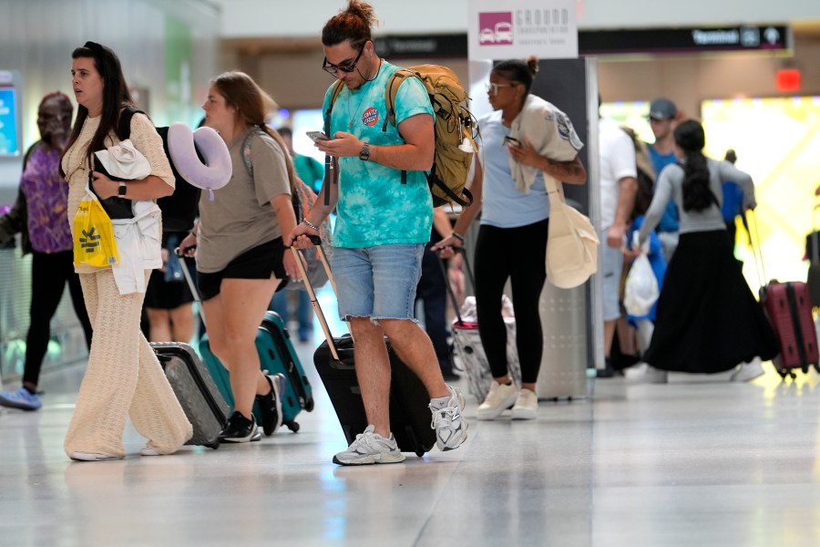 Travelers walk through Miami International Airport, Wednesday, July 3, 2024, in Miami. (AP Photo/Lynne Sladky)