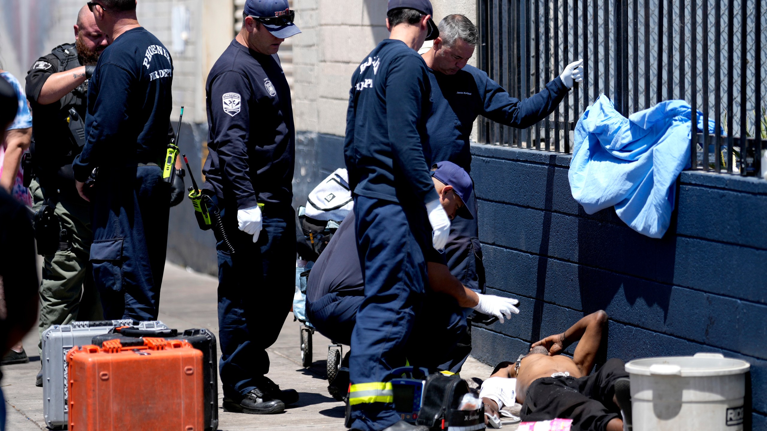 FILE - Phoenix firefighters give medical attention to a homeless man in the heat, May 30, 2024, in Phoenix. Heat is the top cause of weather-related fatalities nationwide. But because investigations of suspected heat deaths can take months, and mishmash of methods counties use to count them, we really don't know exactly how many people died in the most recent heat wave stretching back to July 1 (AP Photo/Matt York, File)