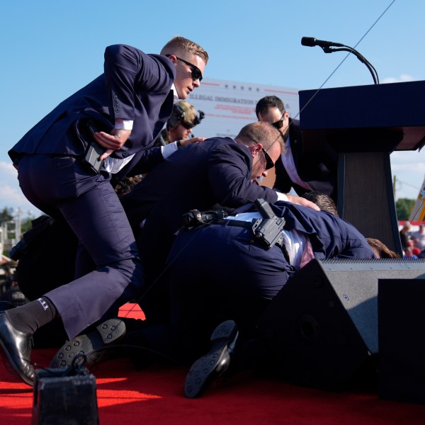 Republican presidential candidate former President Donald Trump is covered by U.S. Secret Service agents at a campaign rally, Saturday, July 13, 2024, in Butler, Pa. (AP Photo/Evan Vucci)