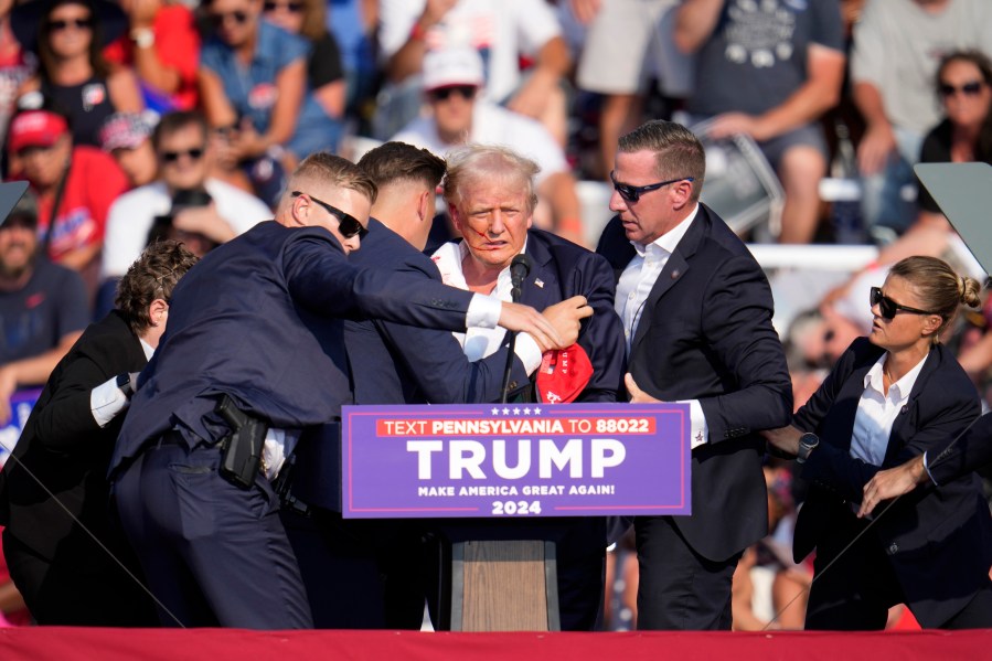 Republican presidential candidate former President Donald Trump is helped off the stage at a campaign event in Butler, Pa., on Saturday, July 13, 2024. (AP Photo/Gene J. Puskar)